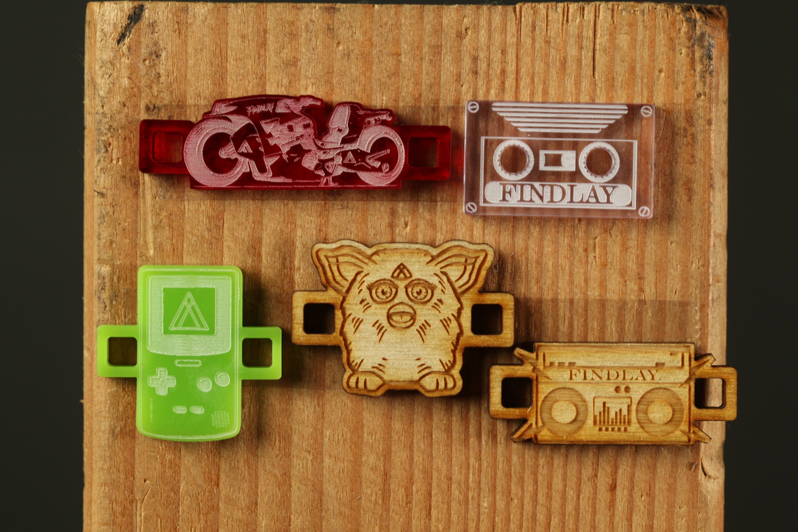 five different objects, including a red object resembling a motorcycle, a clear object resembling a cassette tape, a green object resembling a Nintendo Wii controller, a wooden object resembling a cat, and a wooden object resembling a boombox.