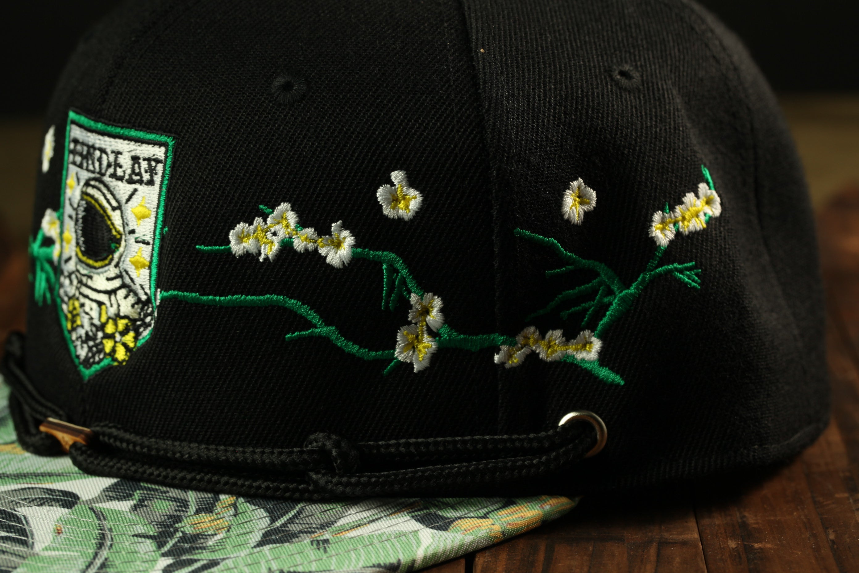 A close-up view of a black baseball cap with a floral embroidered design on the front.