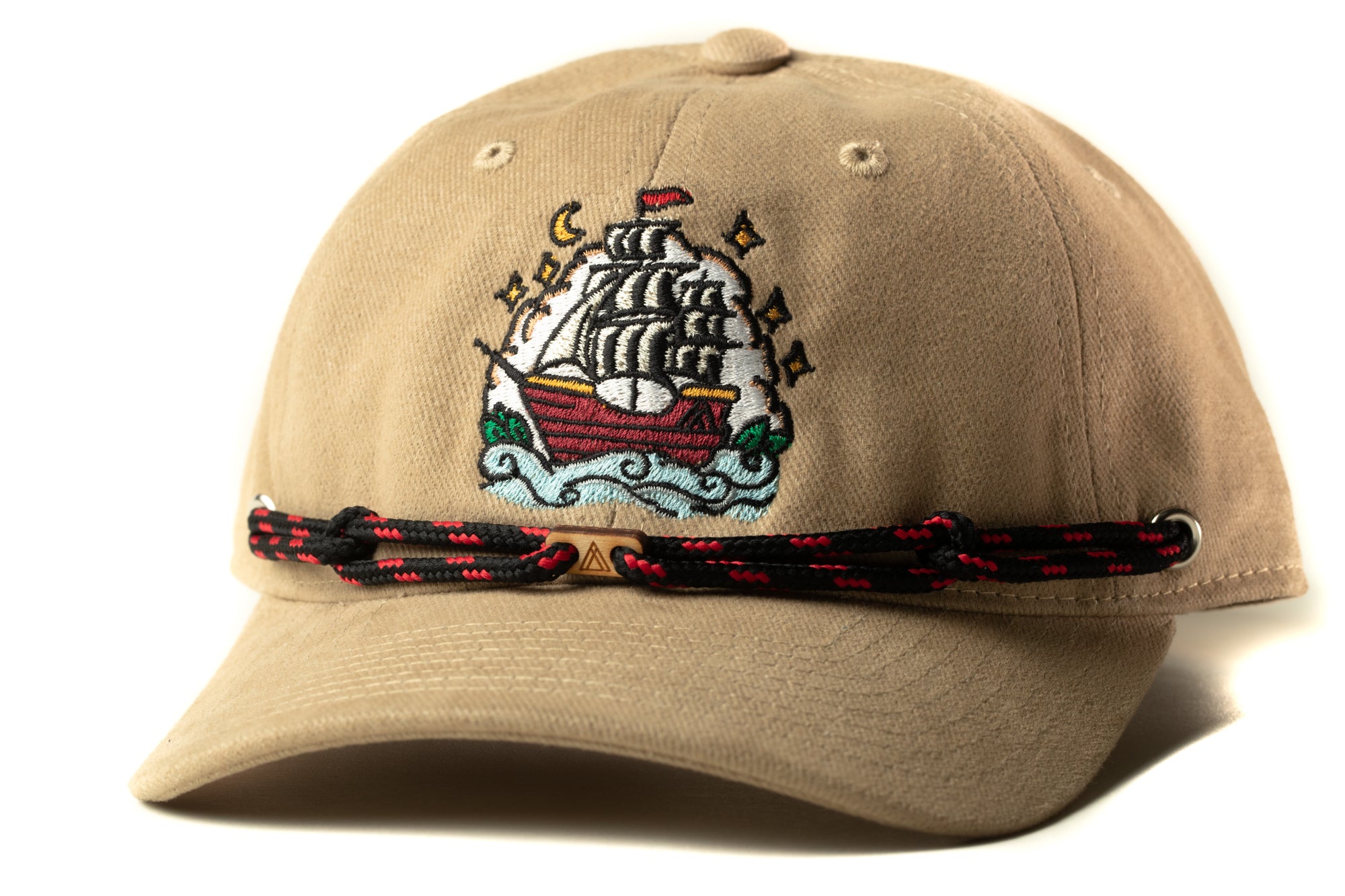 A beige baseball cap with a colorful embroidered design depicting a ship on the front.