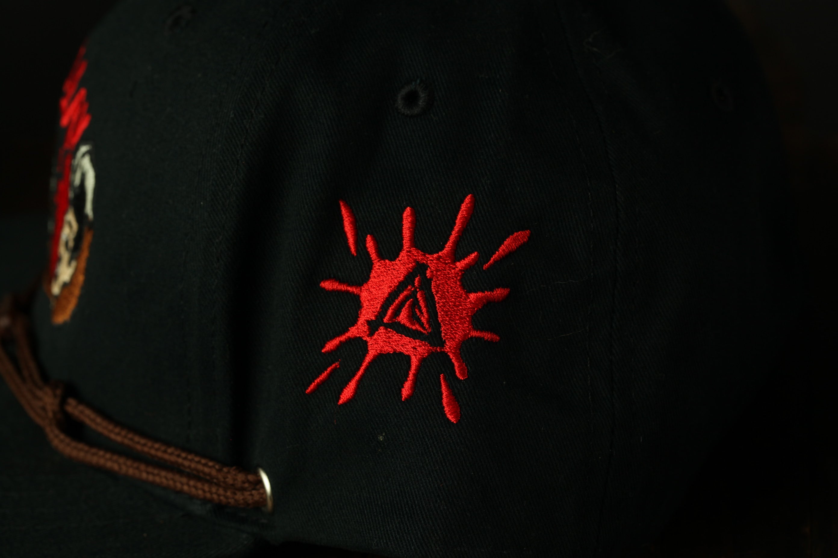 a close-up view of a black baseball cap with a red splash design on the side.