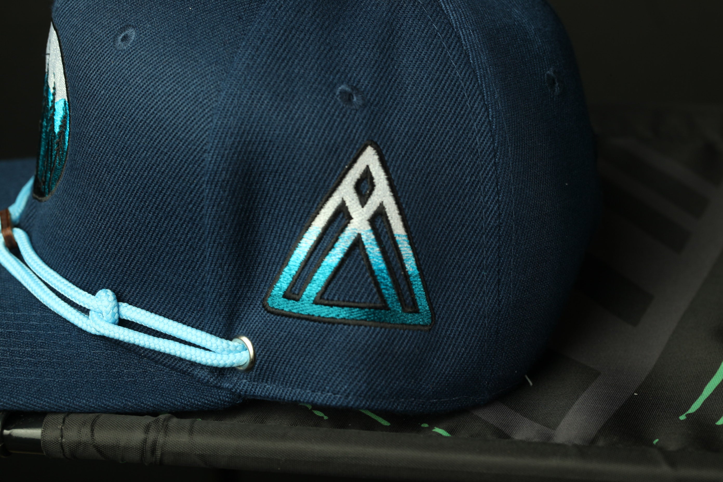 A navy blue baseball cap with a white triangle logo on the front.