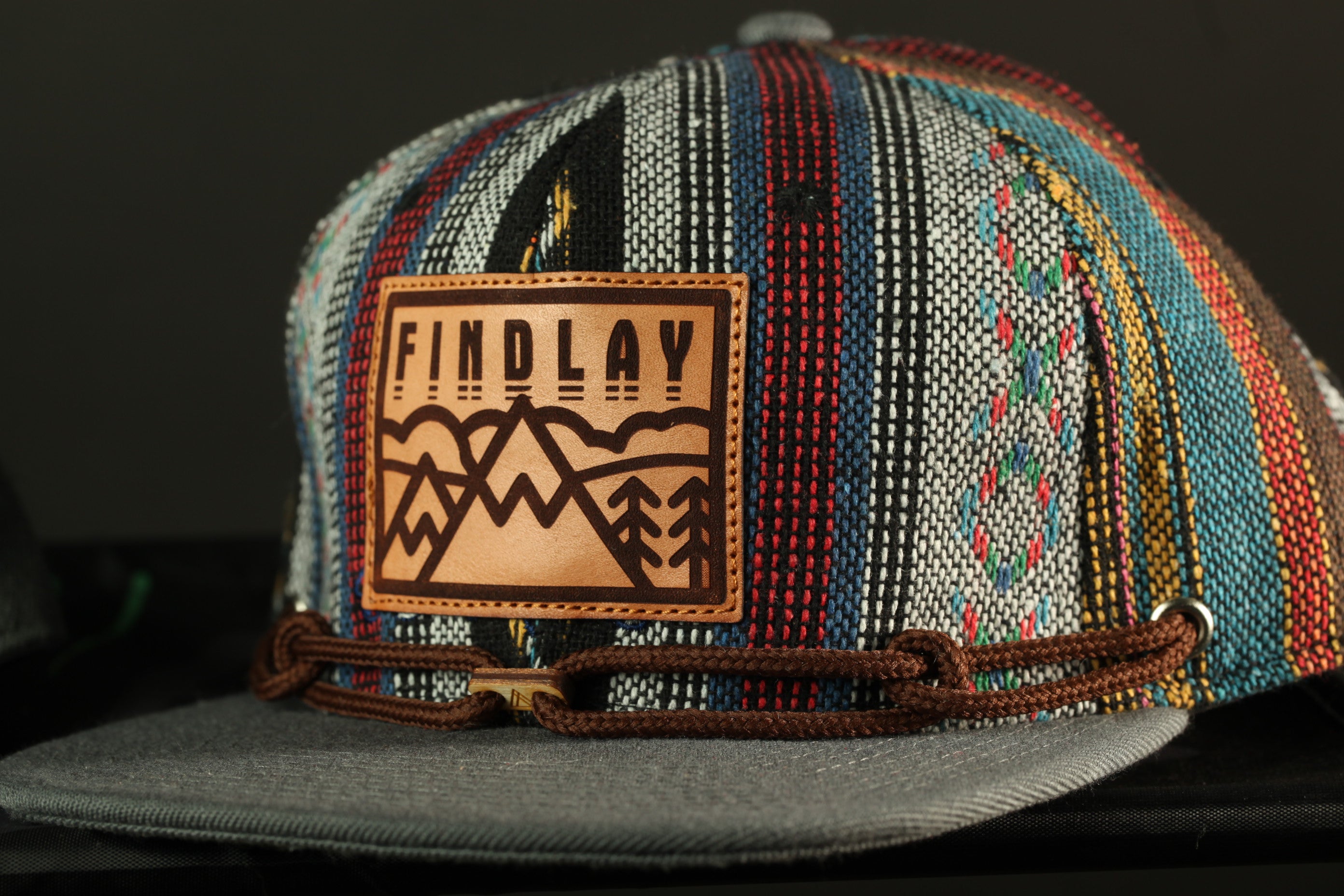 A colorful, patterned baseball cap with a leather patch on the front displaying the text "FINDLAY".