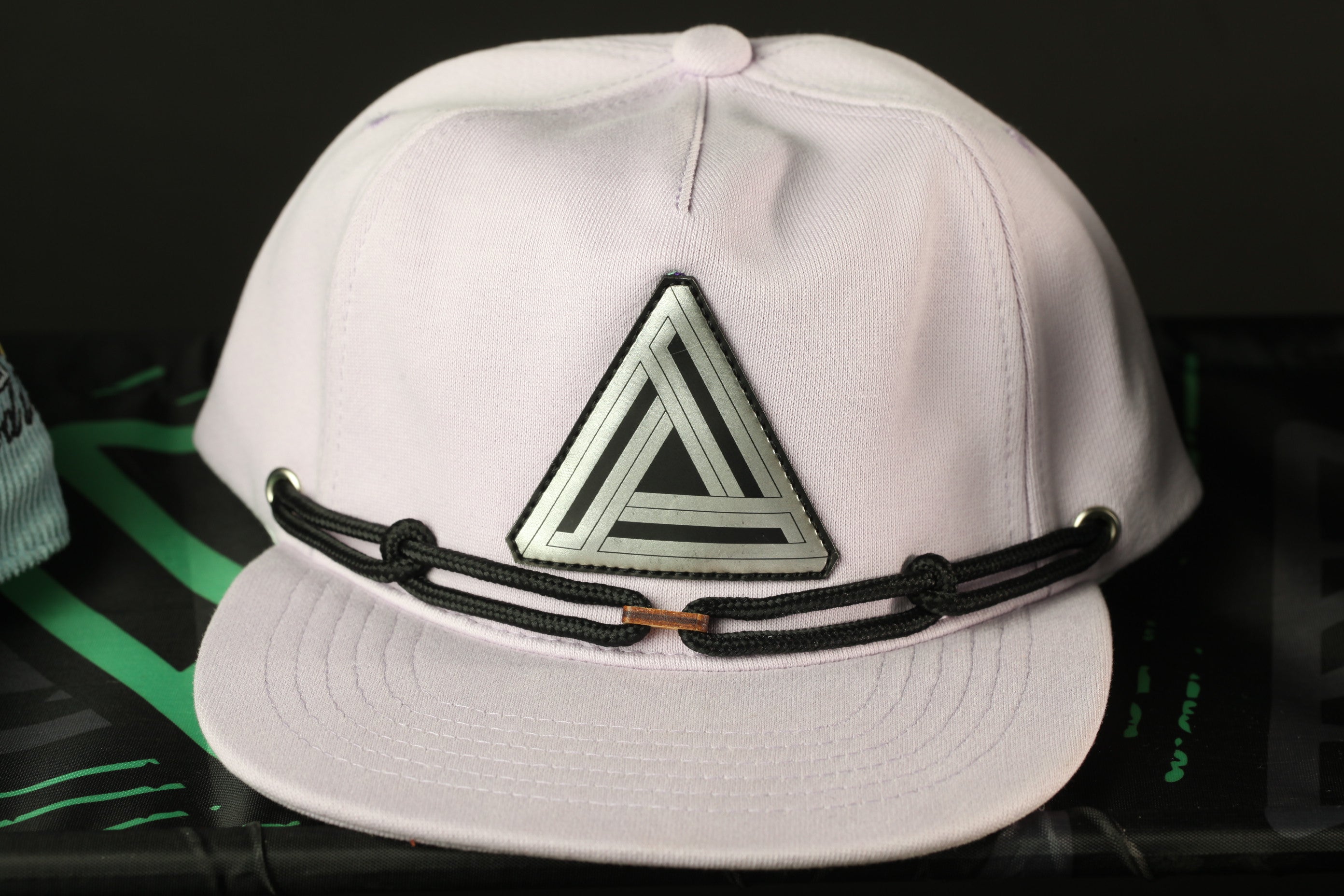 A white baseball cap with a black and silver geometric logo on the front.