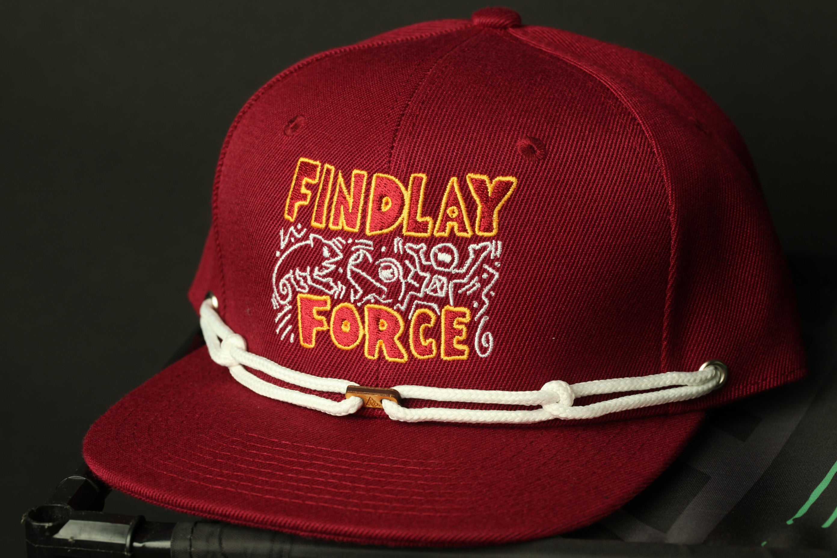 A maroon baseball cap with the text "FINDLAY FORCE" printed on it.