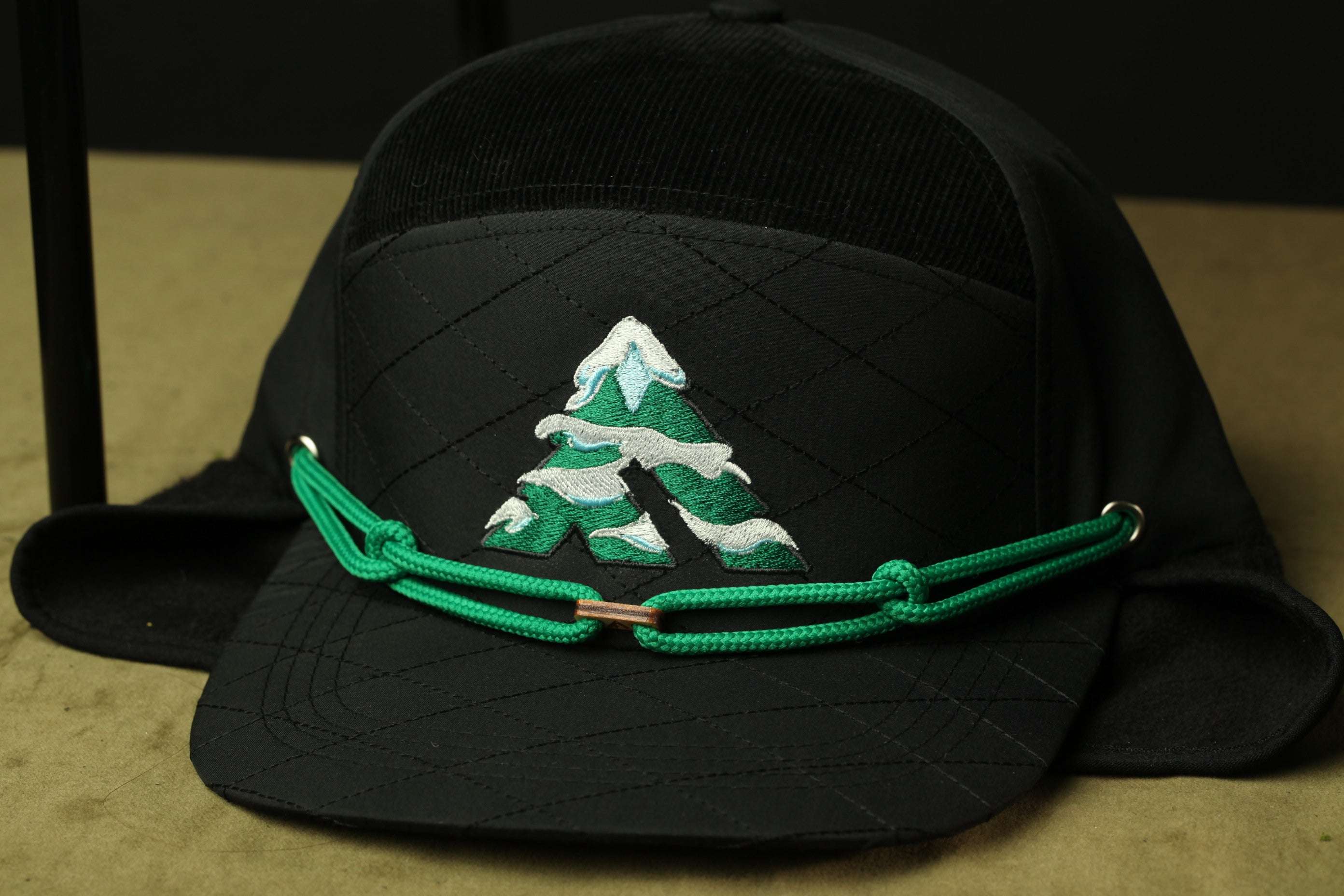 A black baseball cap with a green embroidered logo on the front.