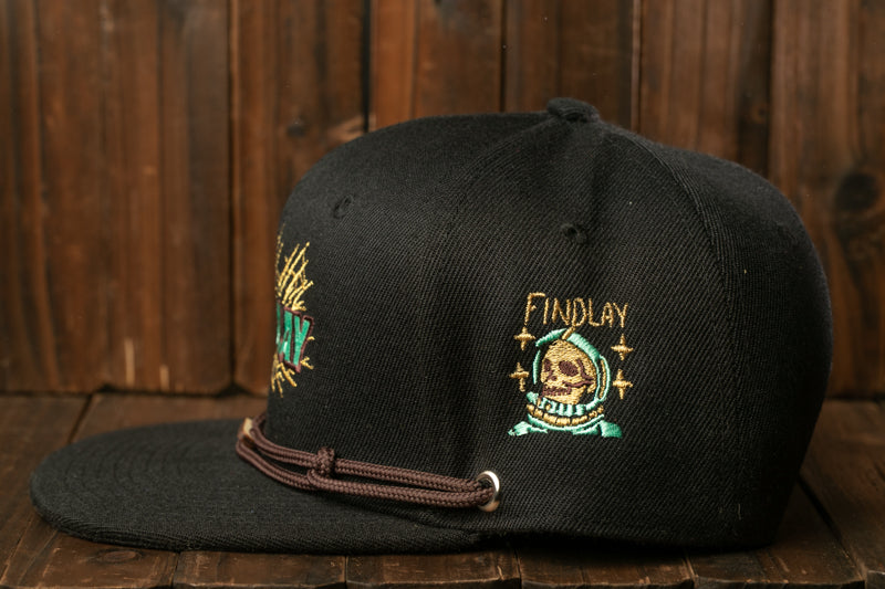 A black baseball cap with embroidered designs on it, including a skull and a skull with a starburst pattern.