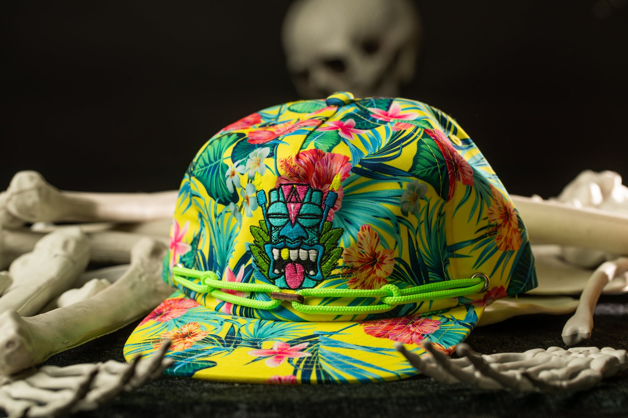 A colorful, patterned baseball cap with a tropical design sits on a surface surrounded by skeletal bones.