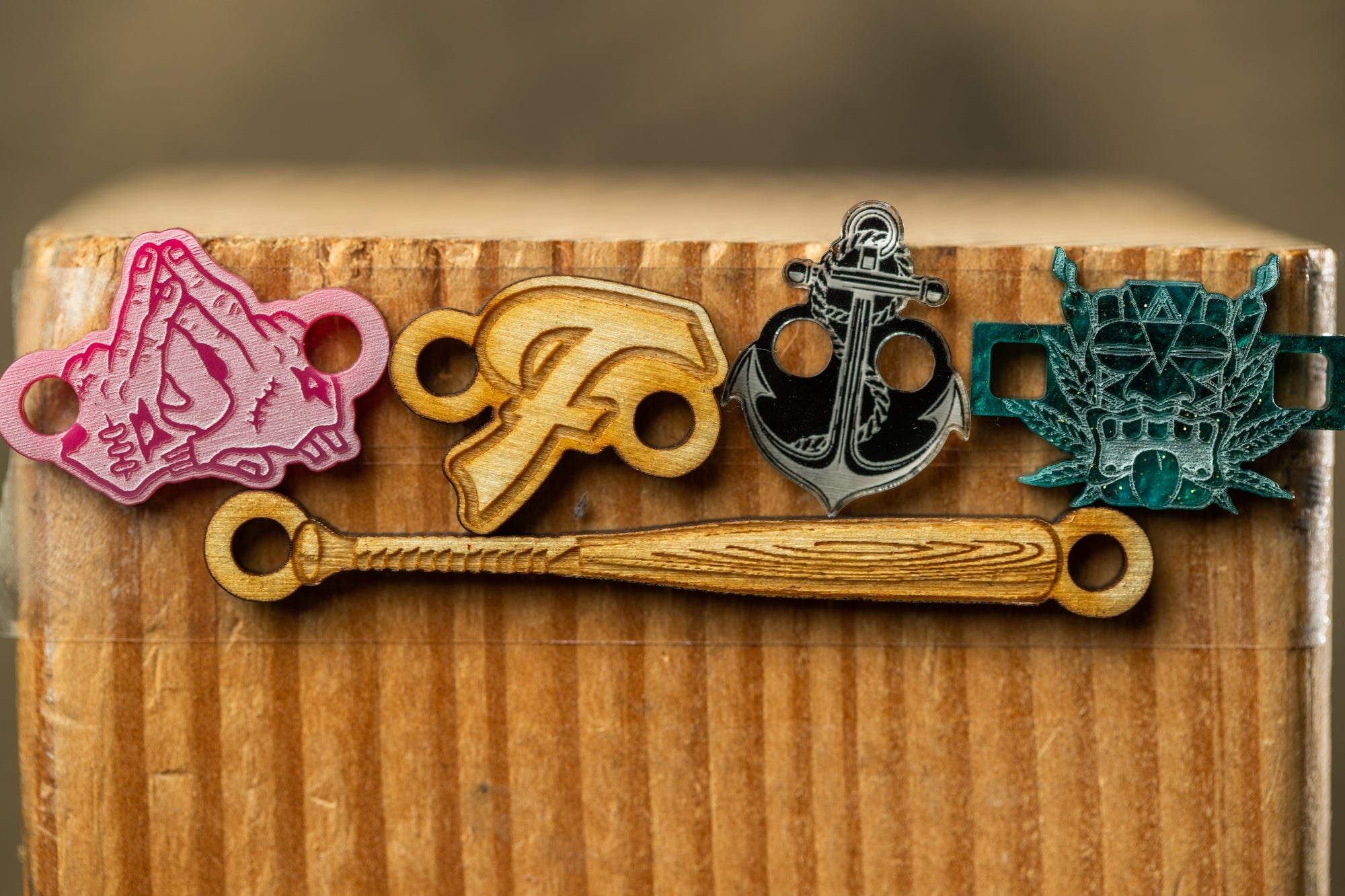 a wooden surface with four distinct wooden objects attached to it, including a bat, an anchor, a skull, and a hand gesture.