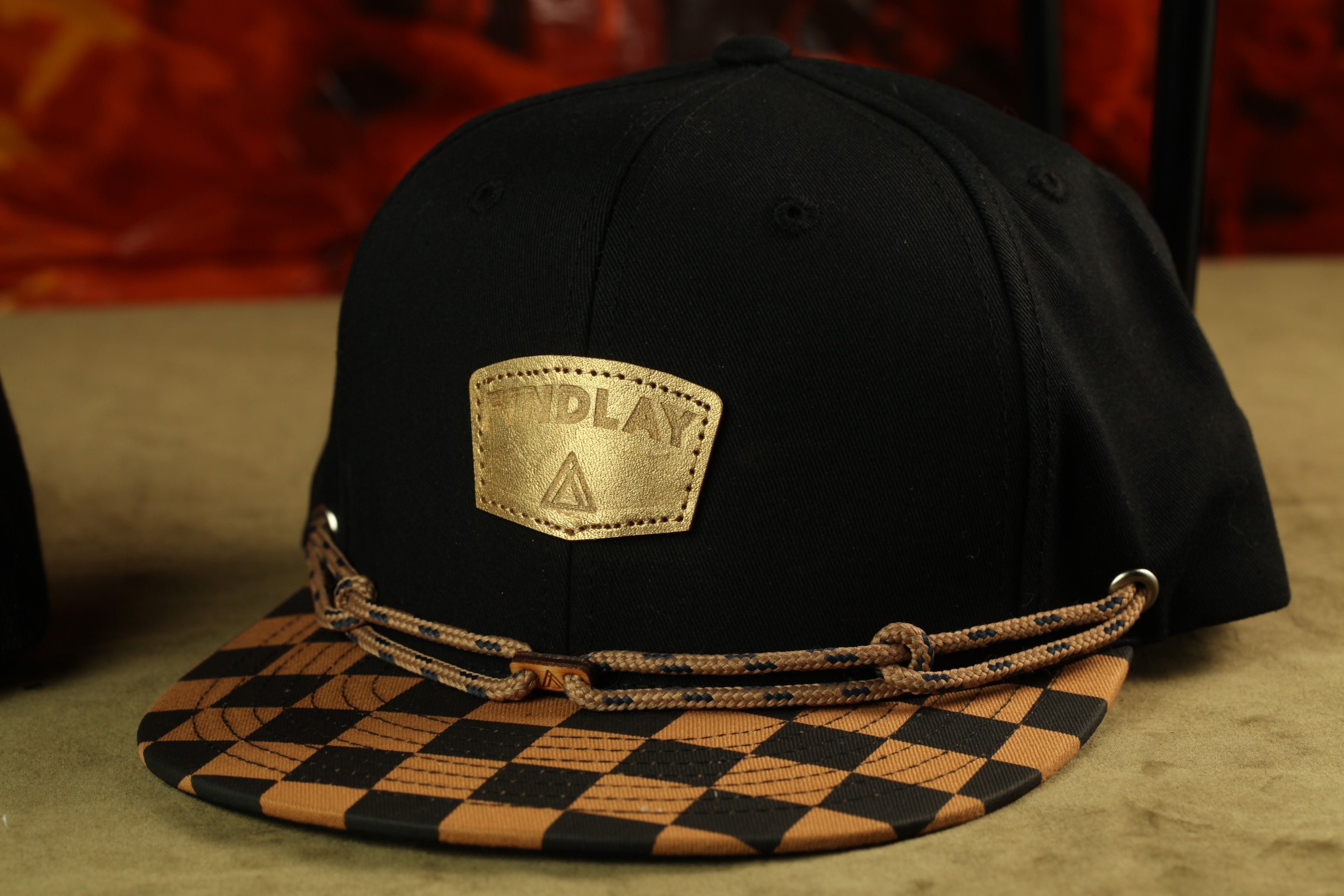 A black baseball cap with a checkered pattern and a gold-colored patch on the front.