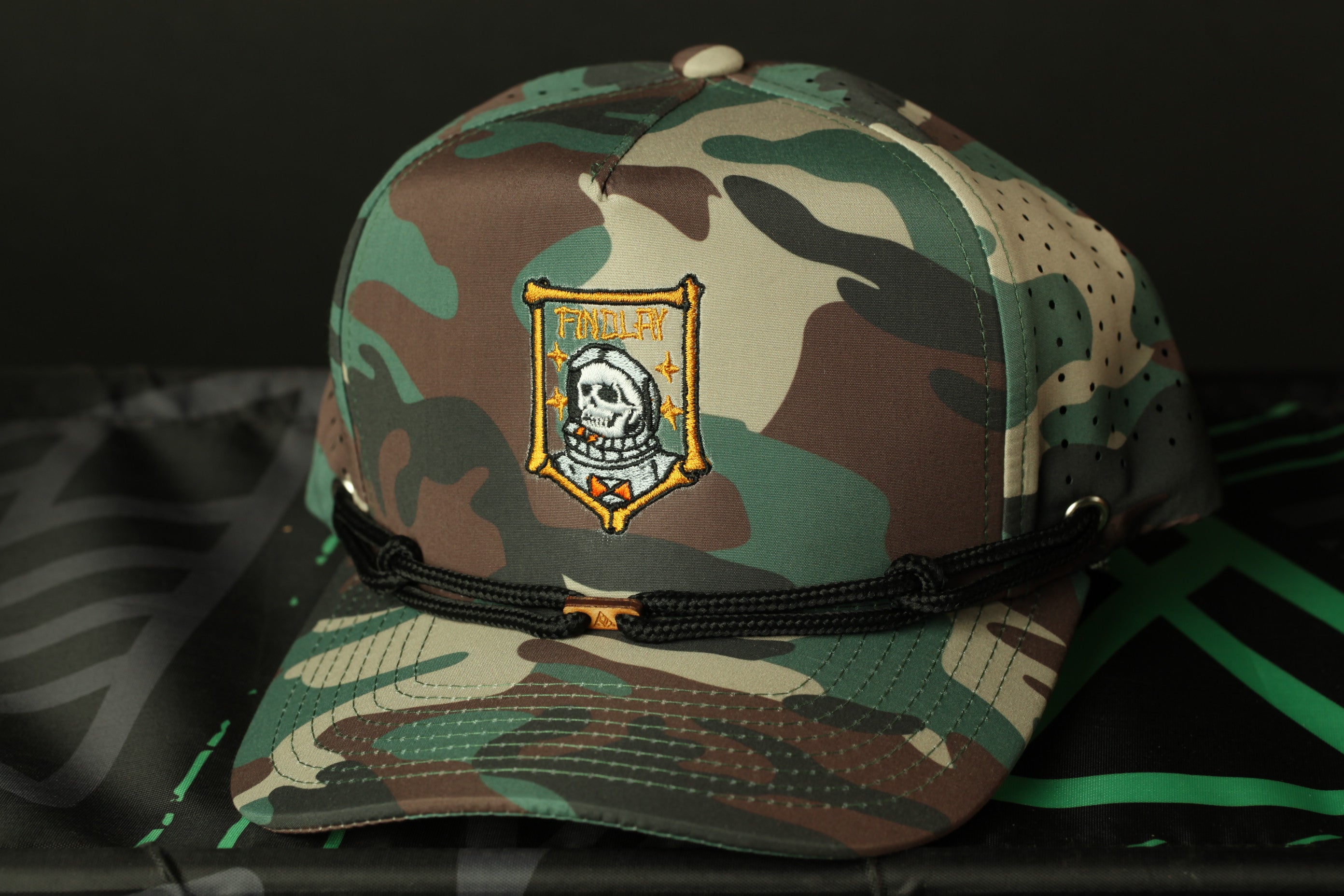 A camouflage baseball cap with a skull and crossbones design on the front.