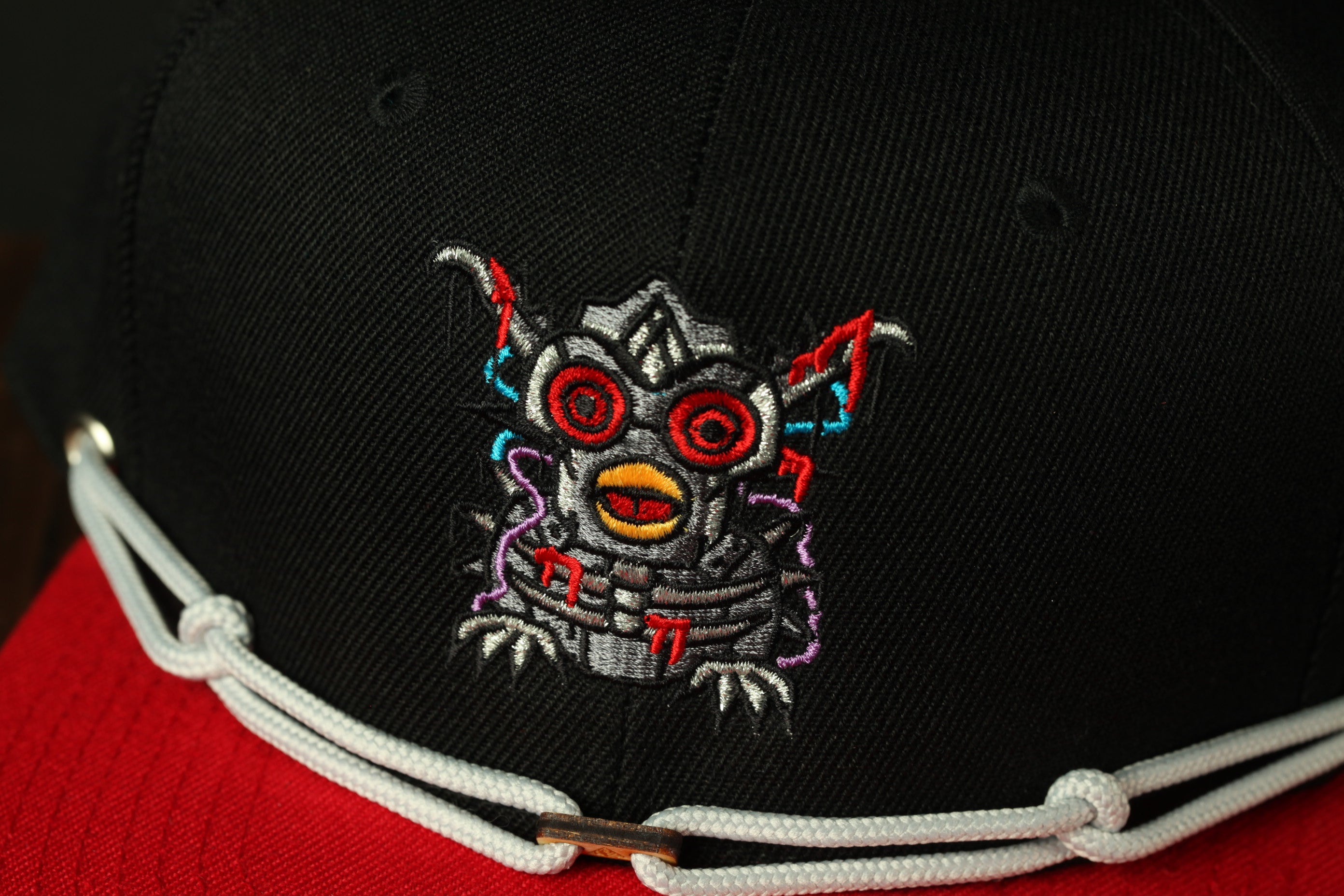 A close-up view of a black baseball cap with a colorful, cartoonish design on the front.