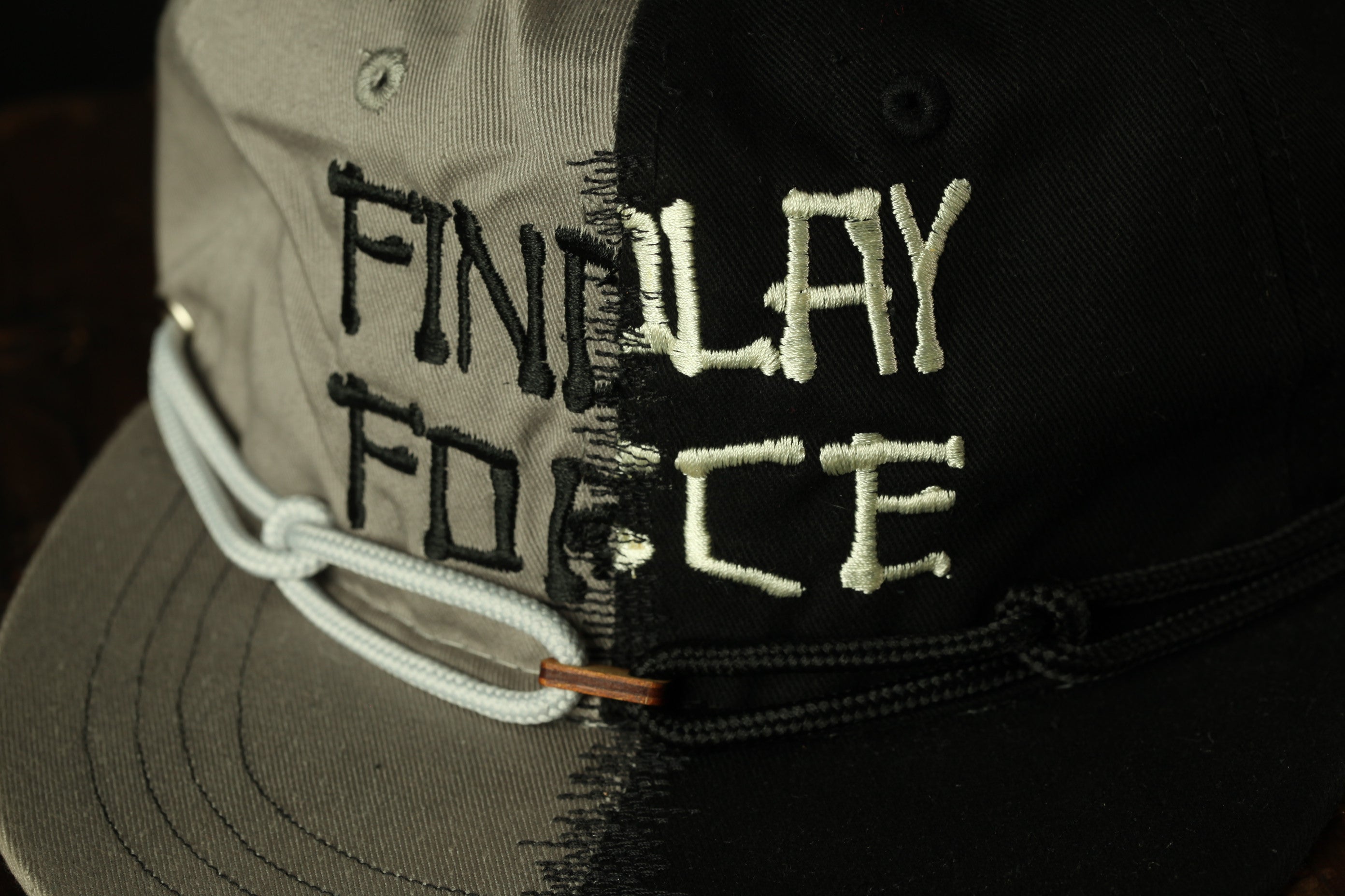 A close-up of a black and gray baseball cap with the text "FINALLY FORCE" embroidered on it.