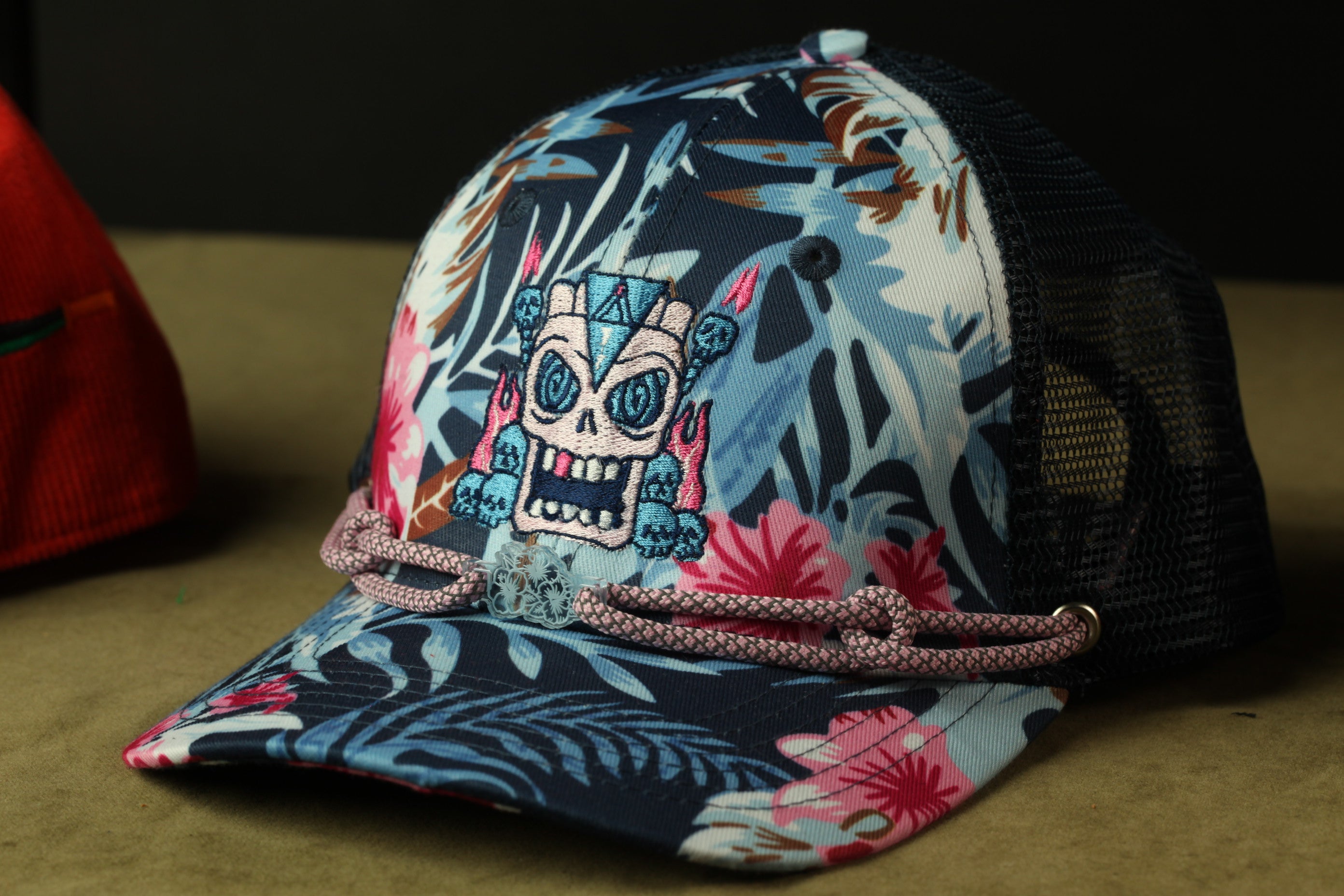 A colorful floral-patterned baseball cap with a skull design on the front, resting on a surface.