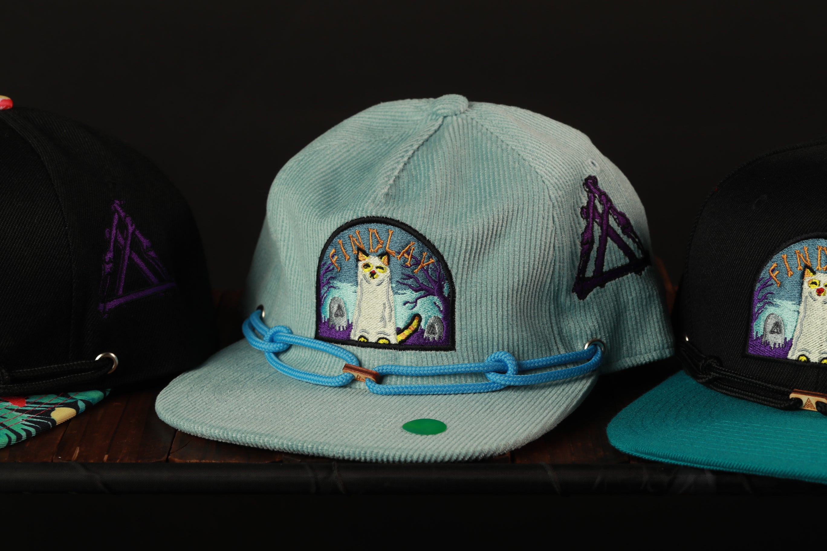 Three baseball caps with different designs and colors are displayed on a shelf.