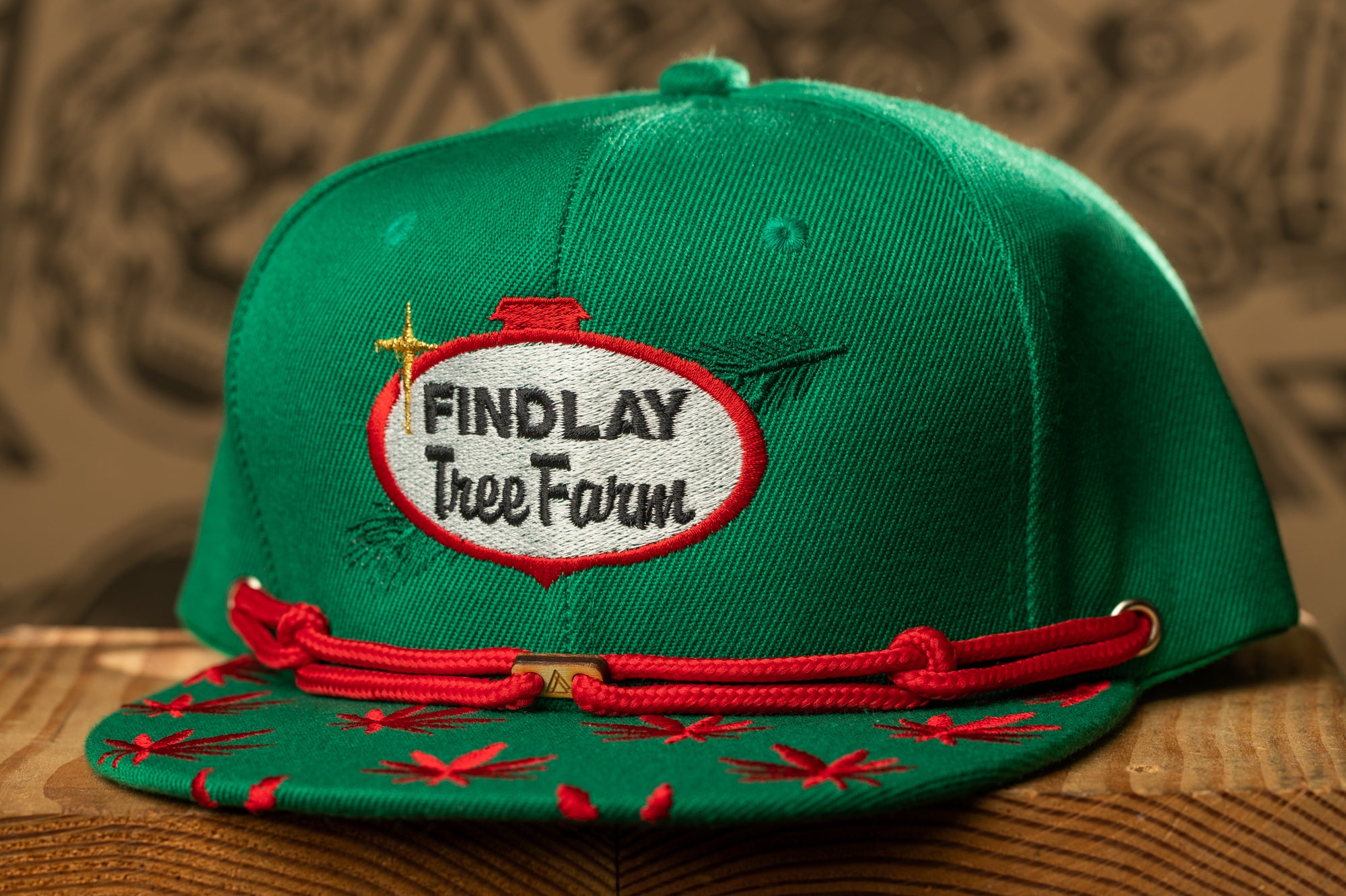 A green baseball cap with a red band and a patch that says "Findlay Tree Farm".