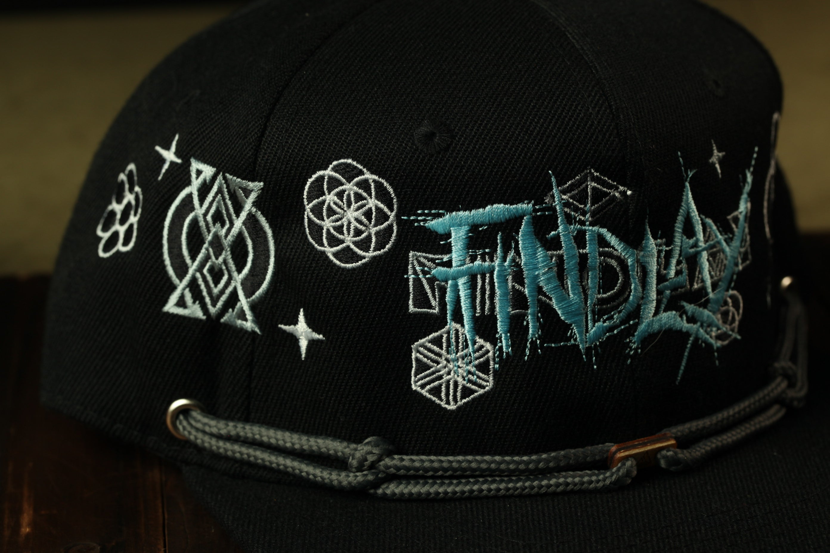 a close-up view of a black baseball cap with various embroidered designs and text on it.