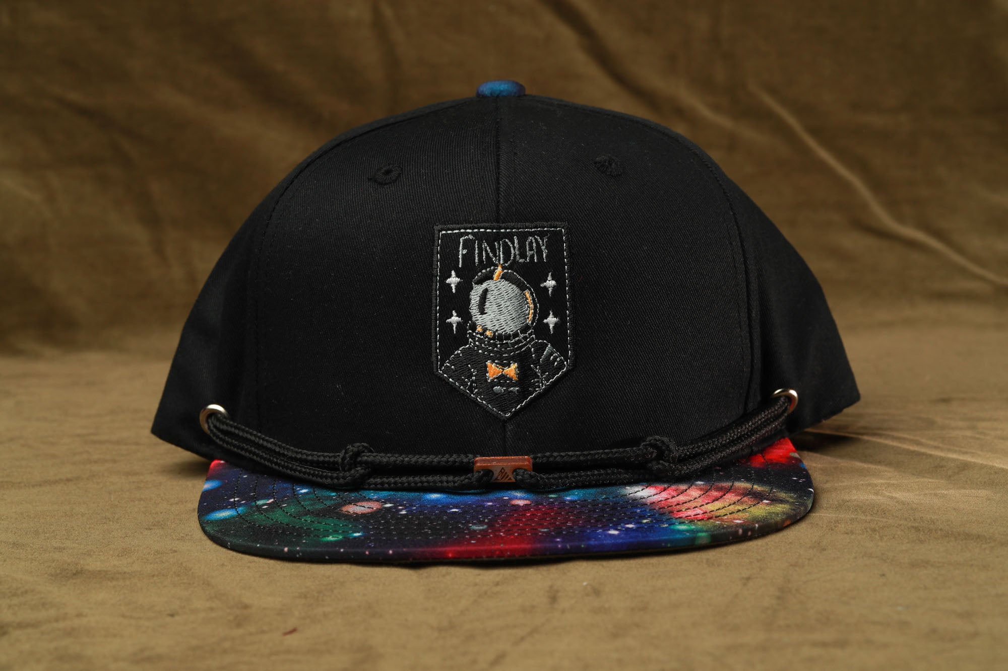 A black baseball cap with a colorful, space-themed design on the front.
