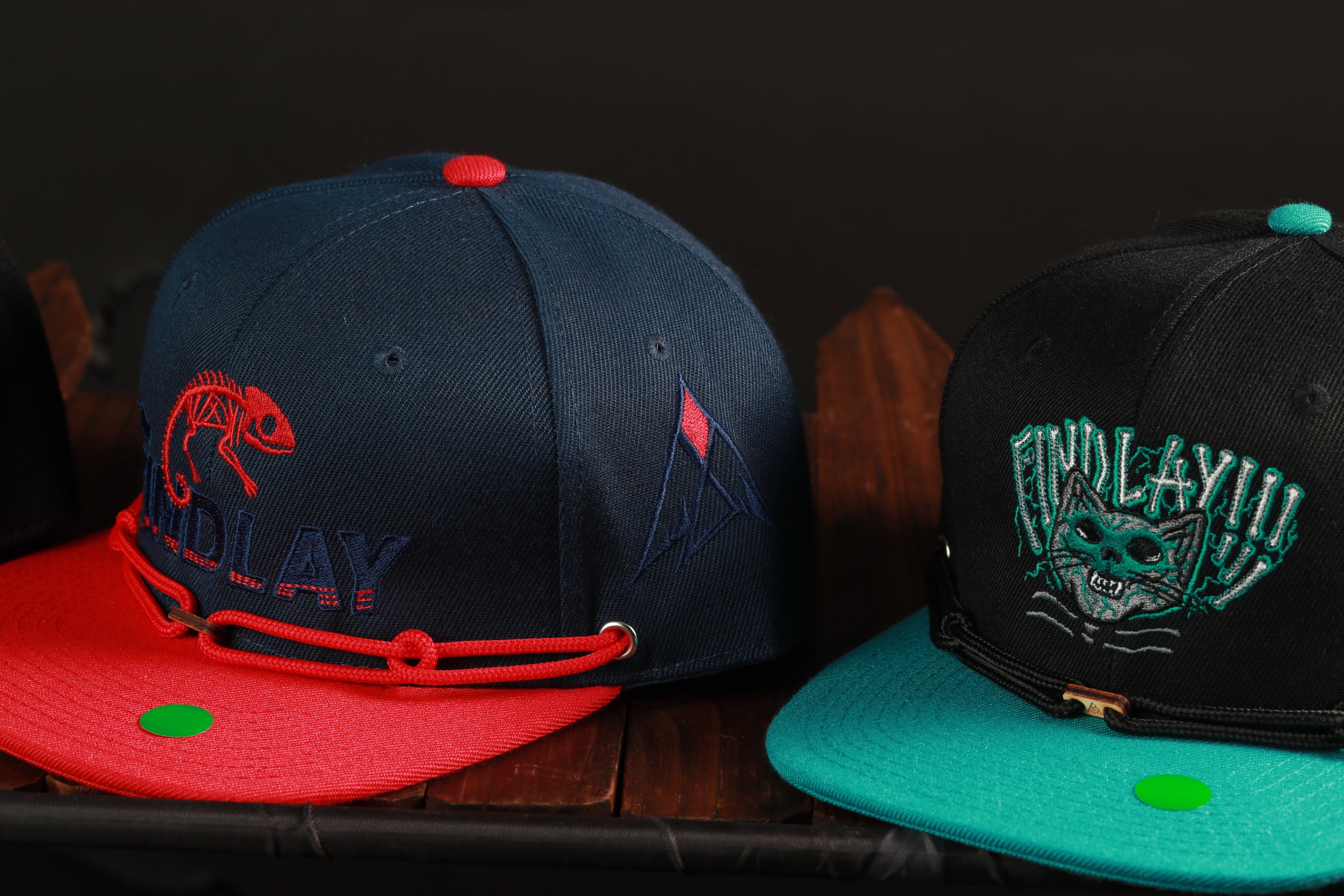 Two baseball caps with different designs and colors are displayed on a wooden surface.