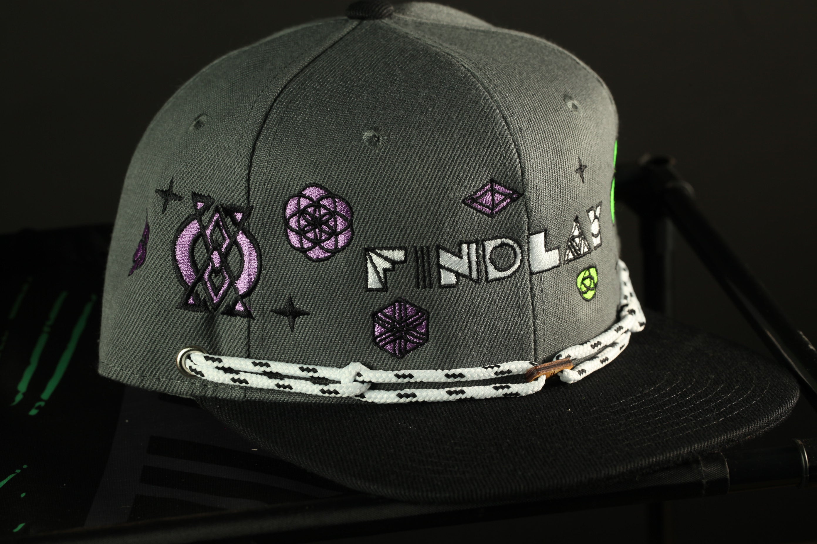A gray baseball cap with various embroidered designs and text on it.