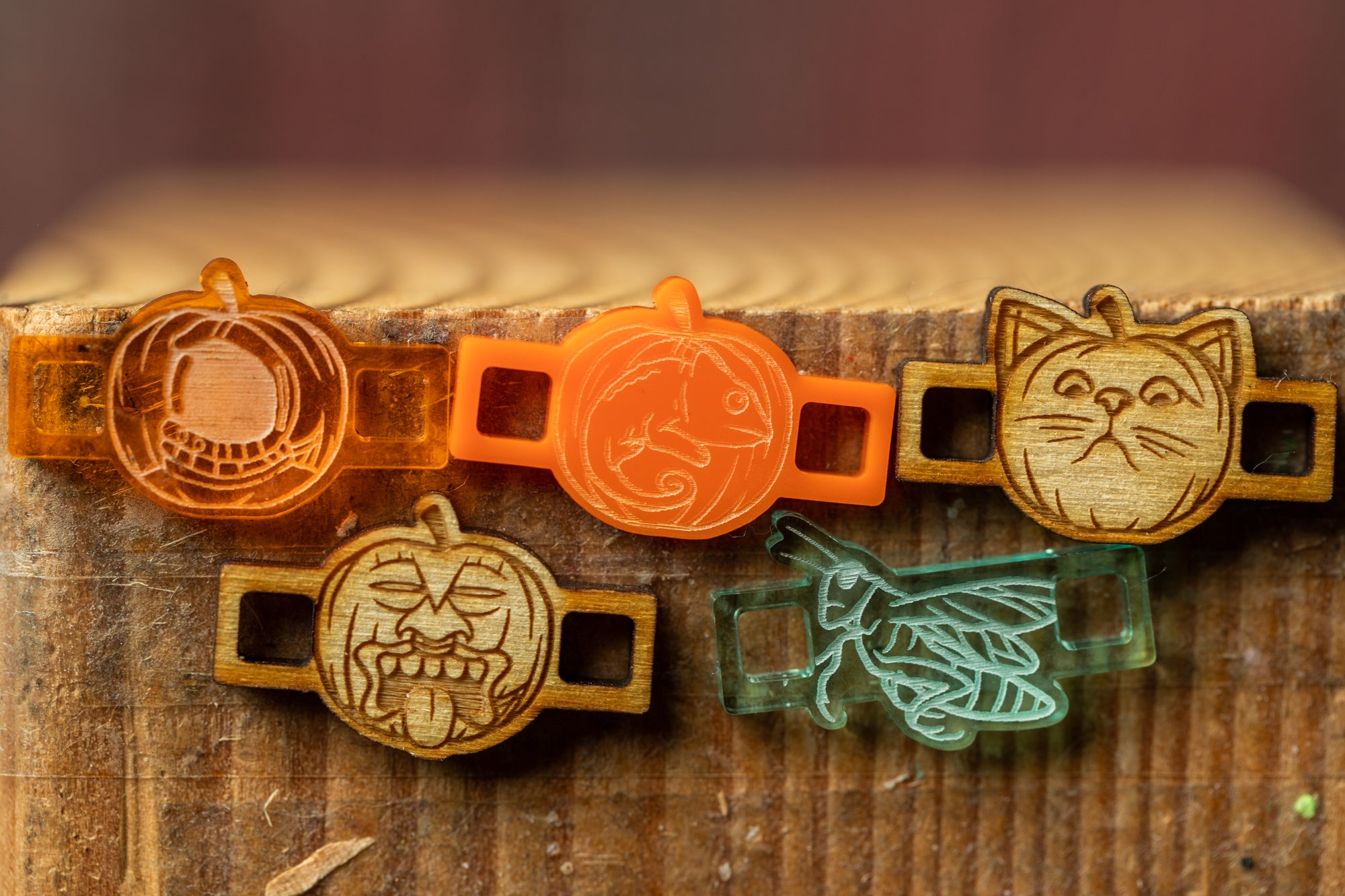 a collection of five wooden charms, each with a unique design, displayed on a wooden surface.