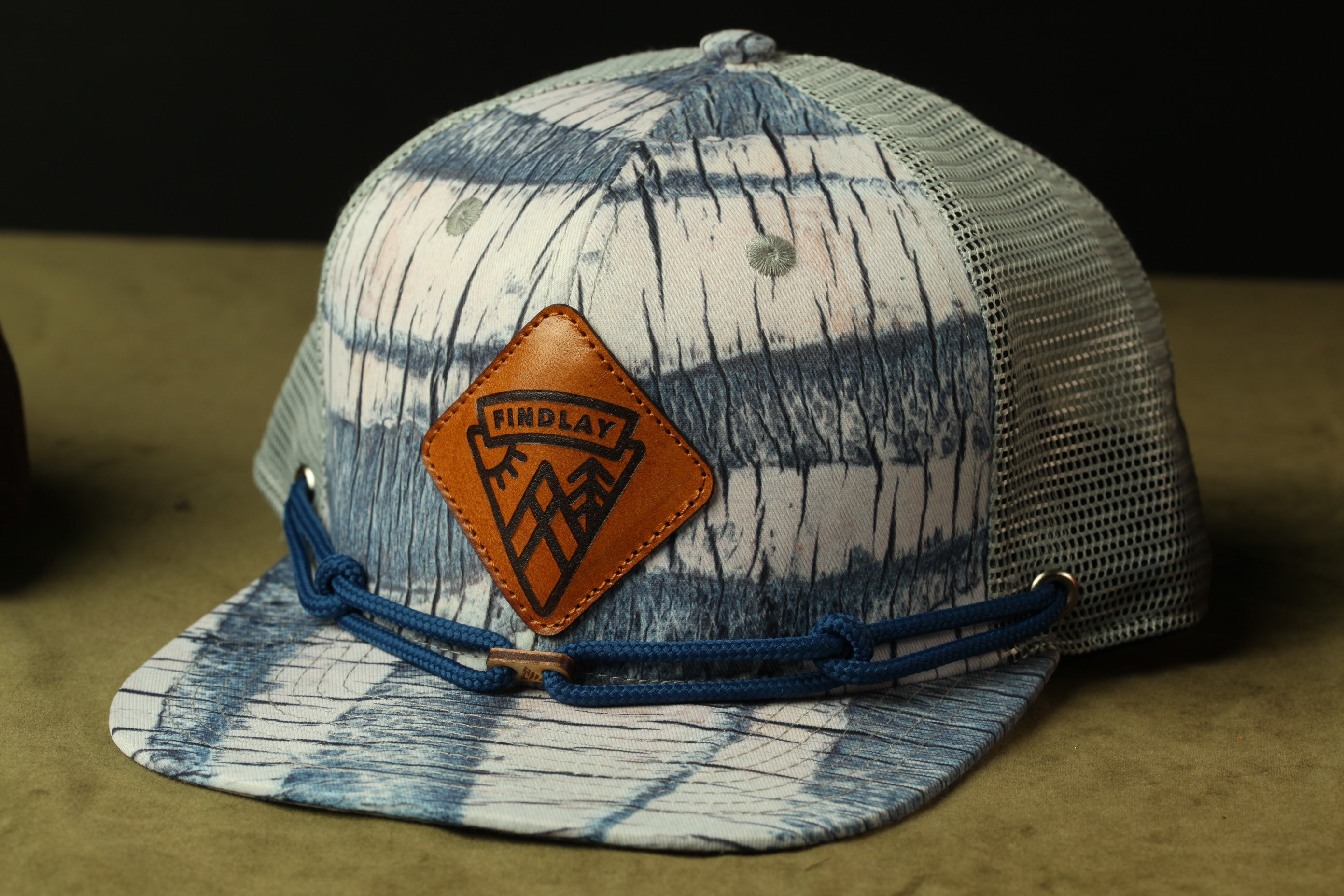 A blue and white patterned baseball cap with a leather patch and blue straps.