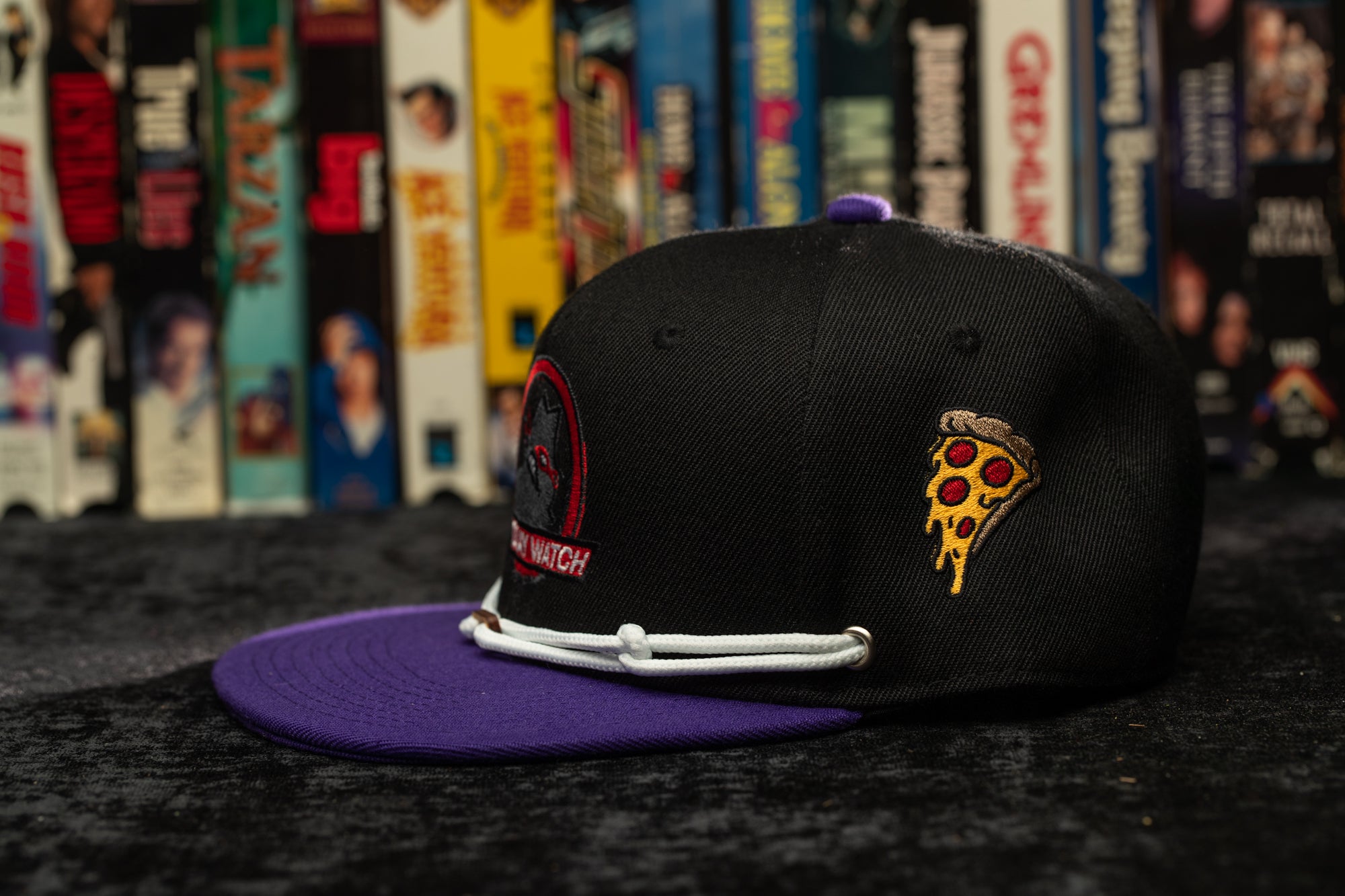 a black and purple hat with a slice of pizza on it