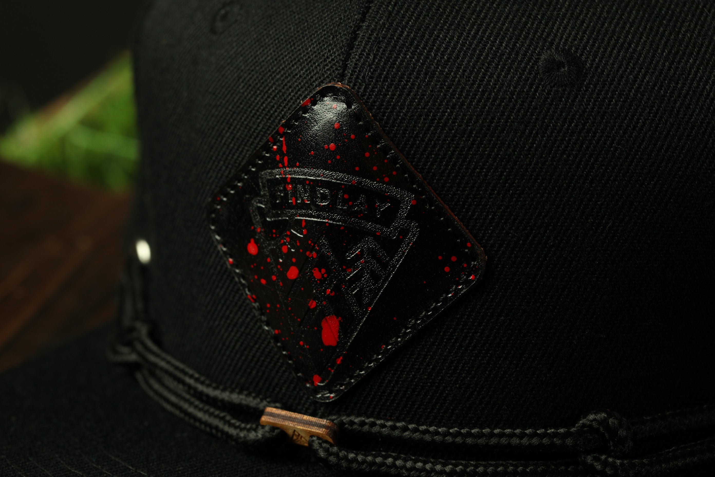 A close-up view of a black baseball cap with a red and black patch featuring the word "ANDAY" on it.