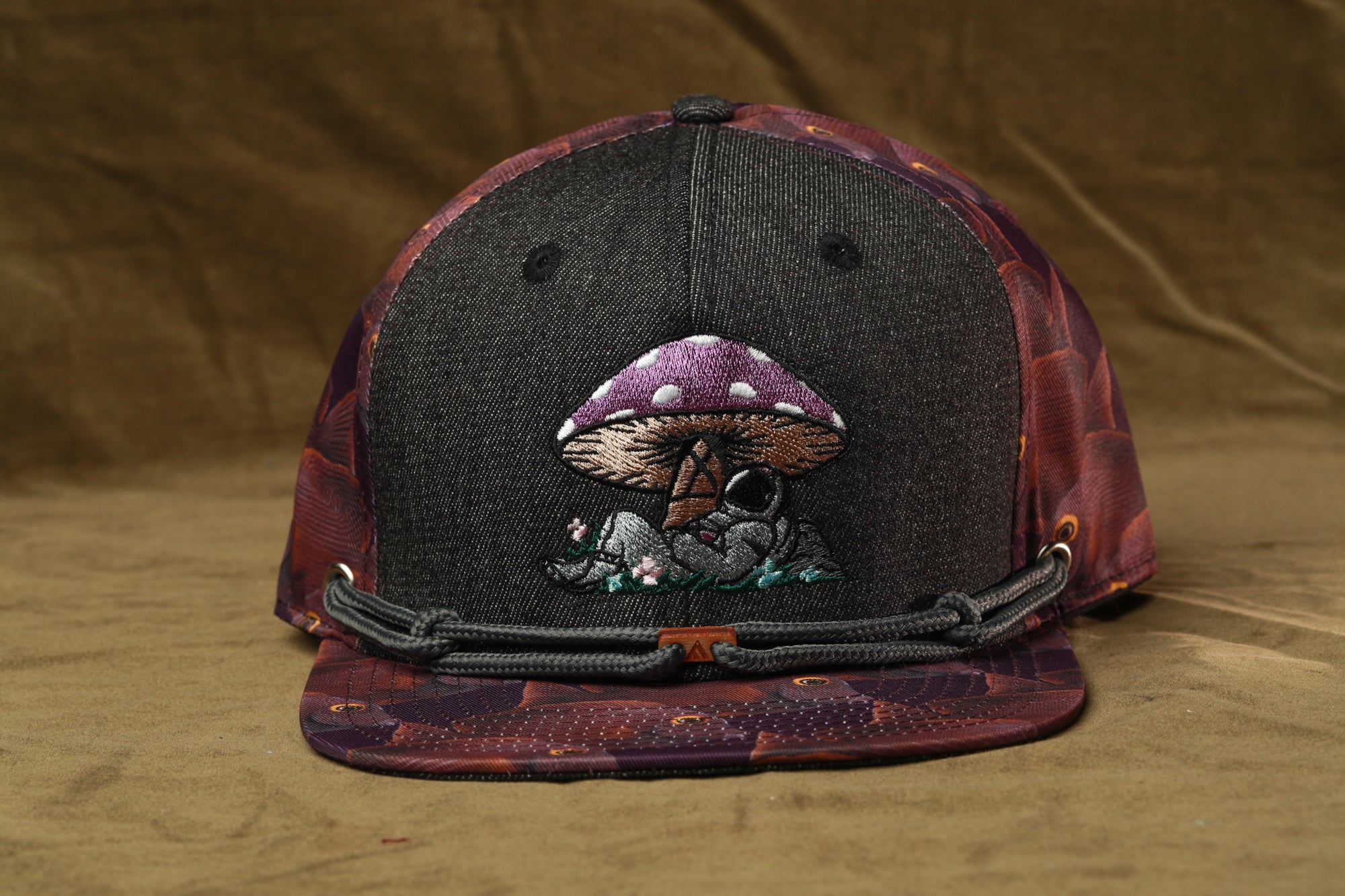 A black baseball cap with a mushroom design on the front.