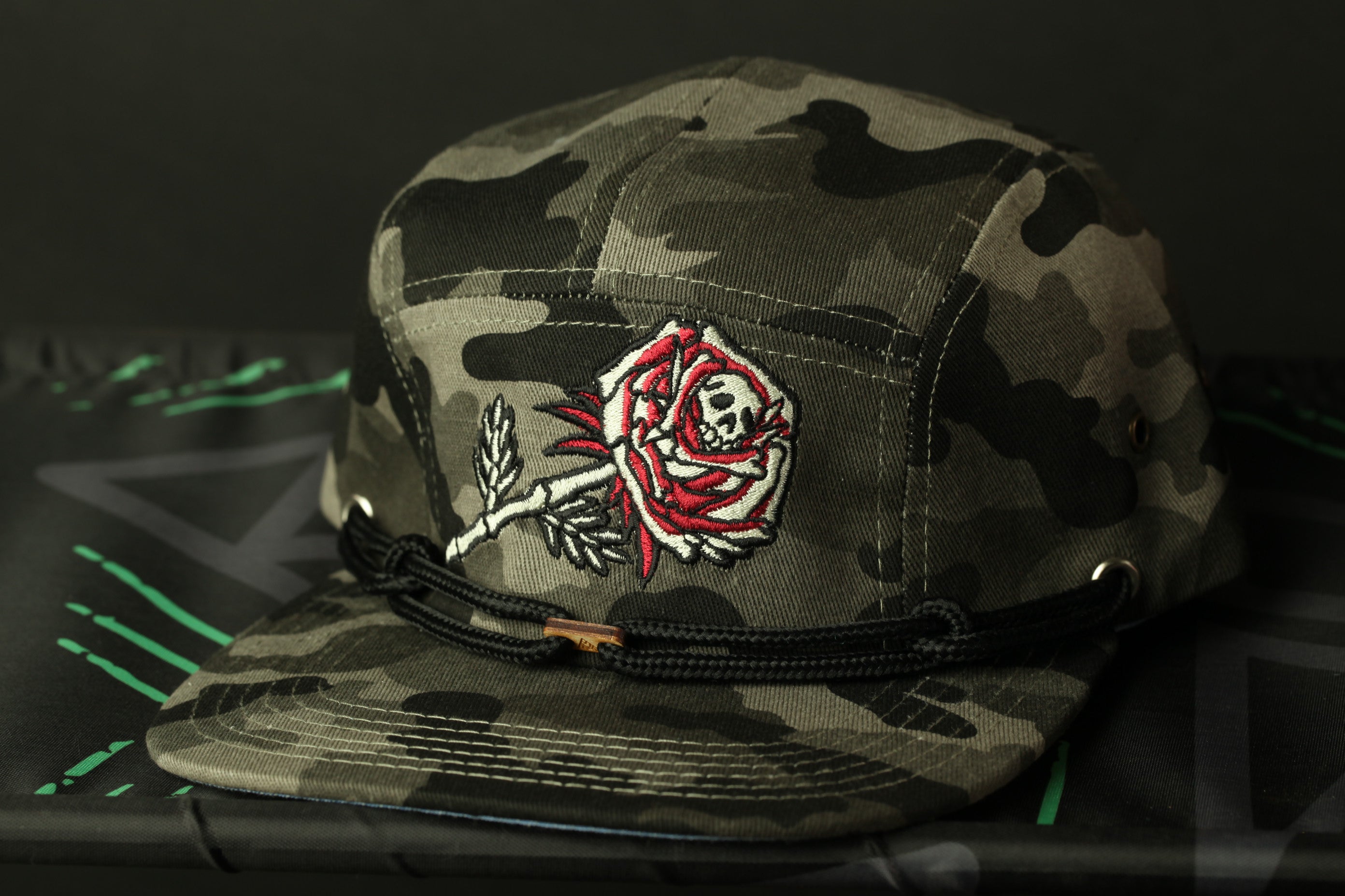 A camouflage baseball cap with a red rose embroidered on the front.