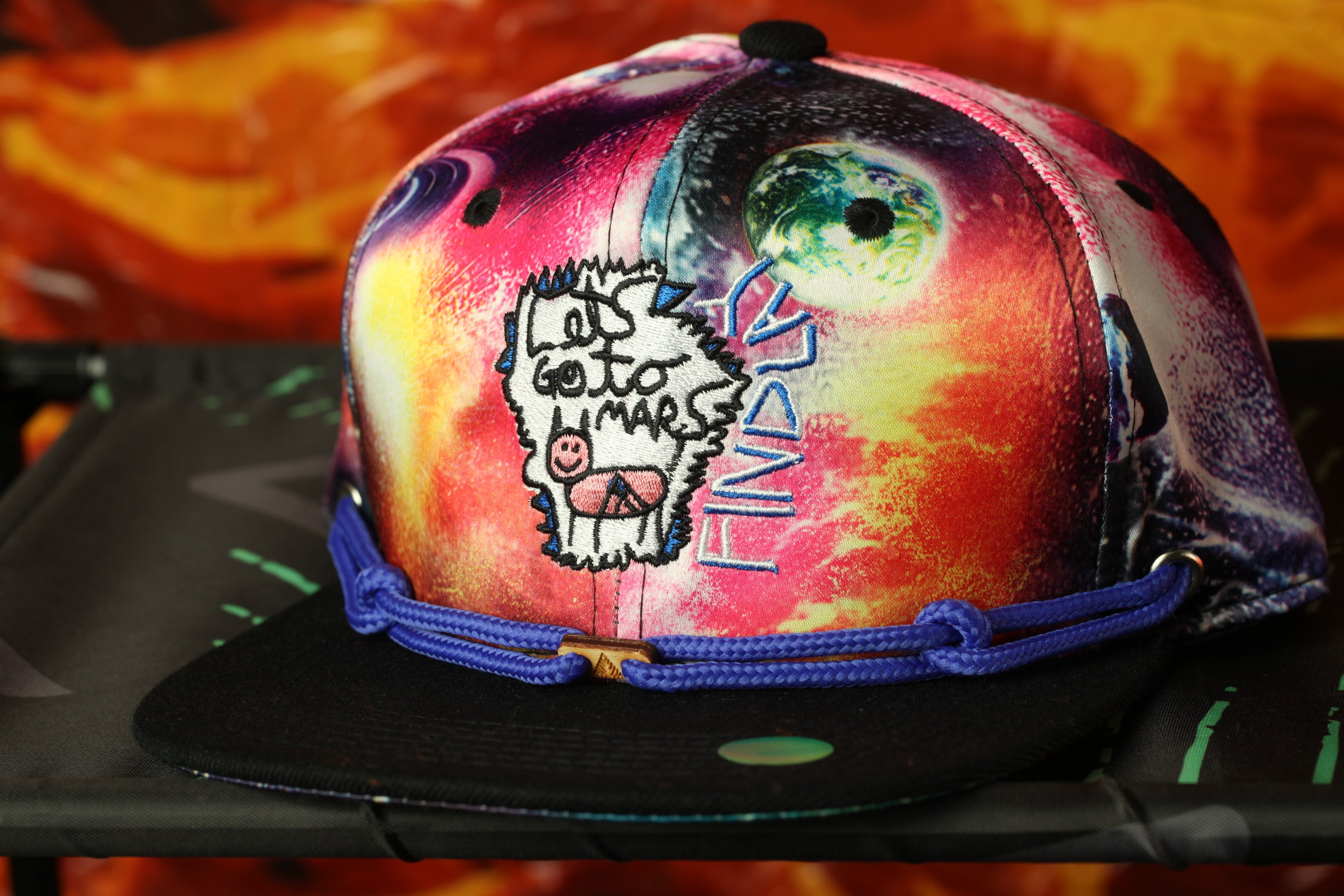 A colorful, patterned baseball cap with a cartoon character design and a peace sign.