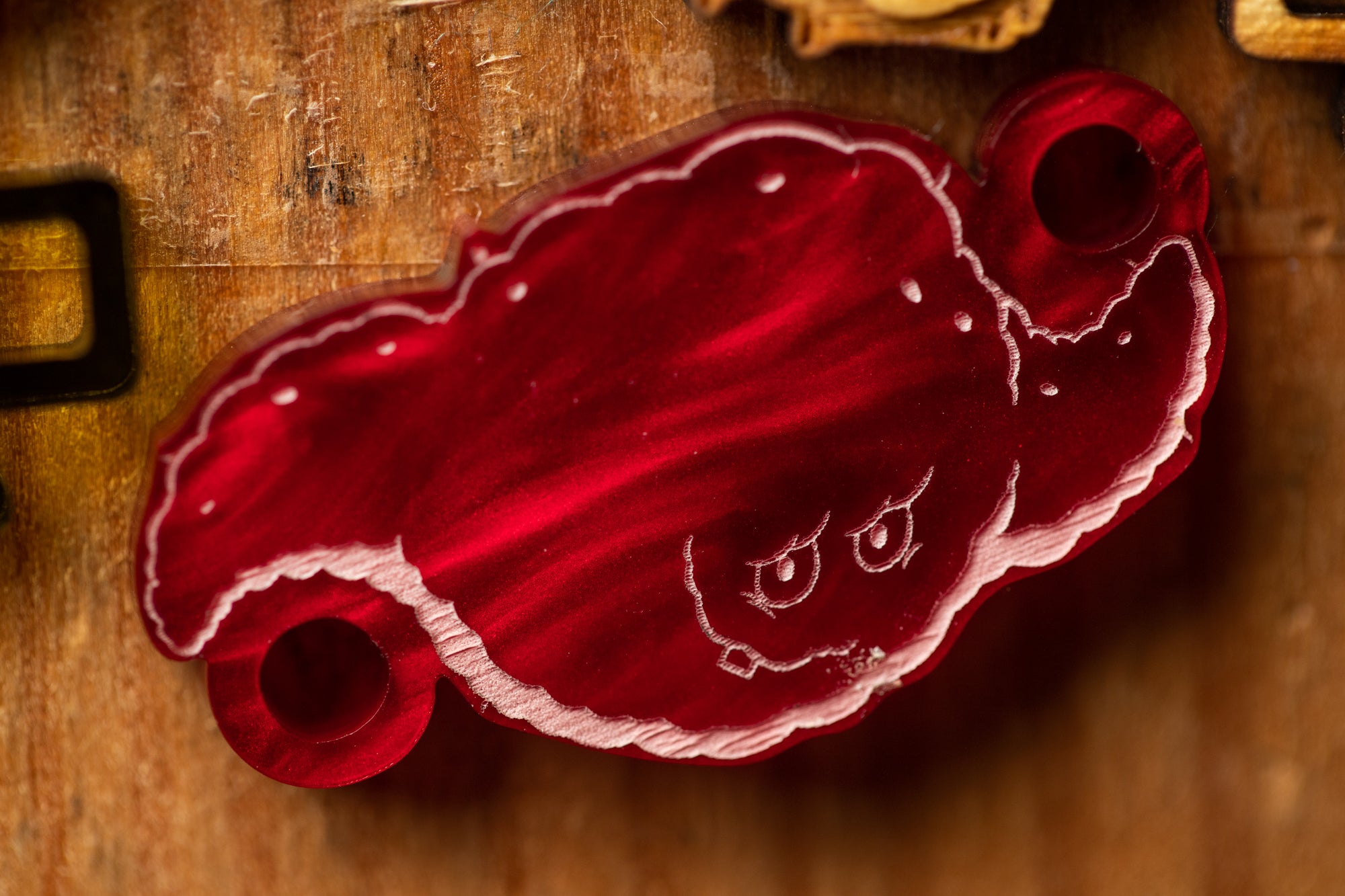 a red, cloud-like object with a face drawn on it, sitting on a wooden surface.