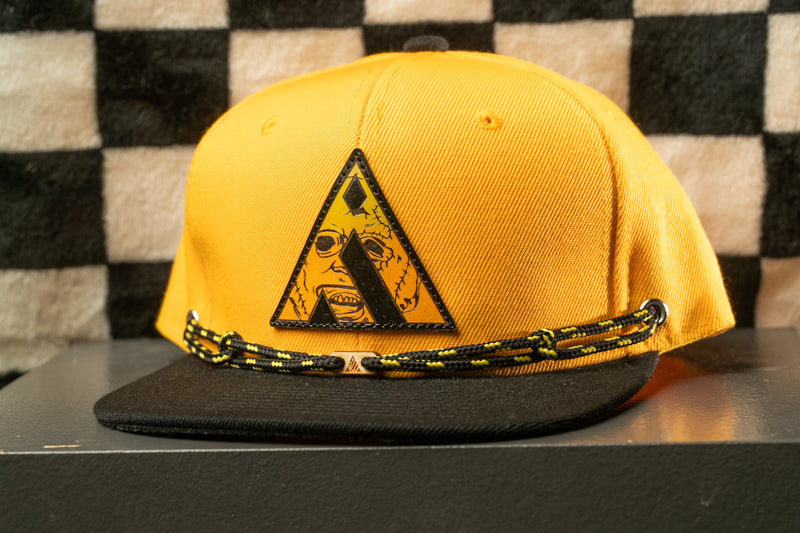 A yellow baseball cap with a black brim and a black and yellow design on the front.