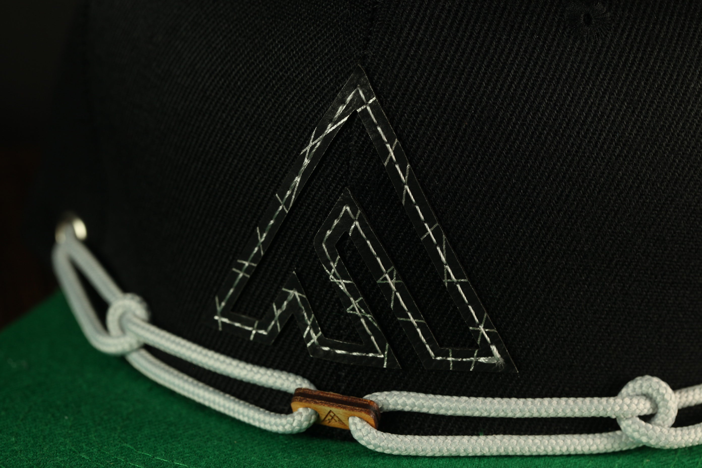 A close-up view of a black baseball cap with a white stitching pattern and a small logo on the front.