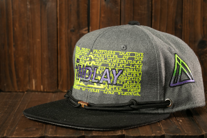 A gray baseball cap with a black brim and a yellow and purple design on the front, sitting on a wooden surface.
