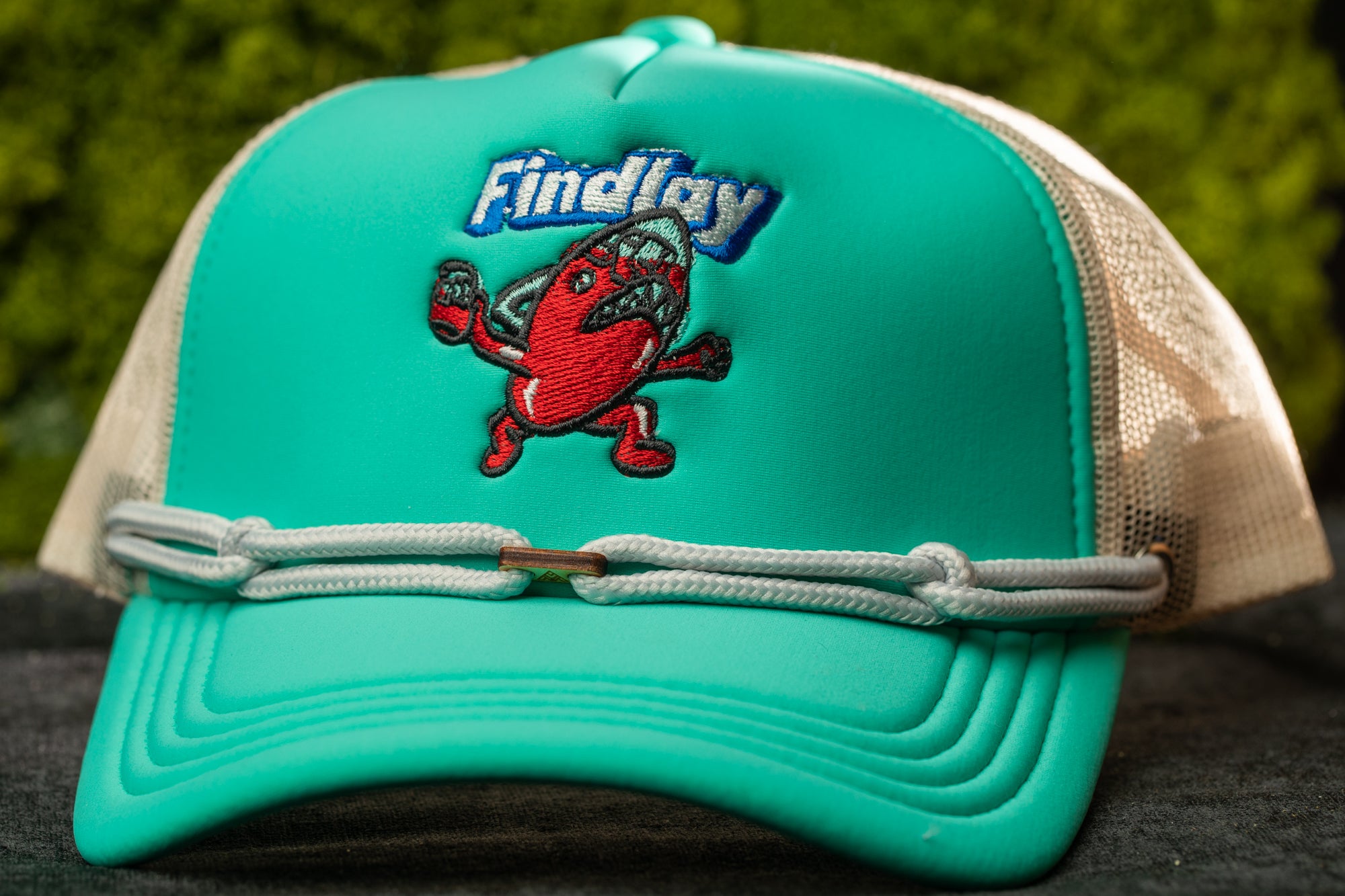 A turquoise baseball cap with a cartoon character on it, featuring the word "Findlay" on the front.