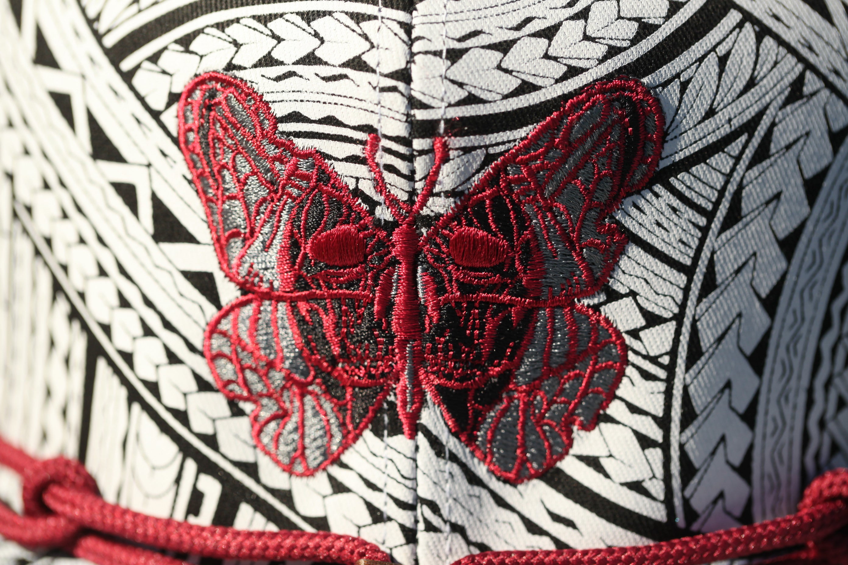 a close-up view of a red butterfly embroidered on a white and black patterned fabric.