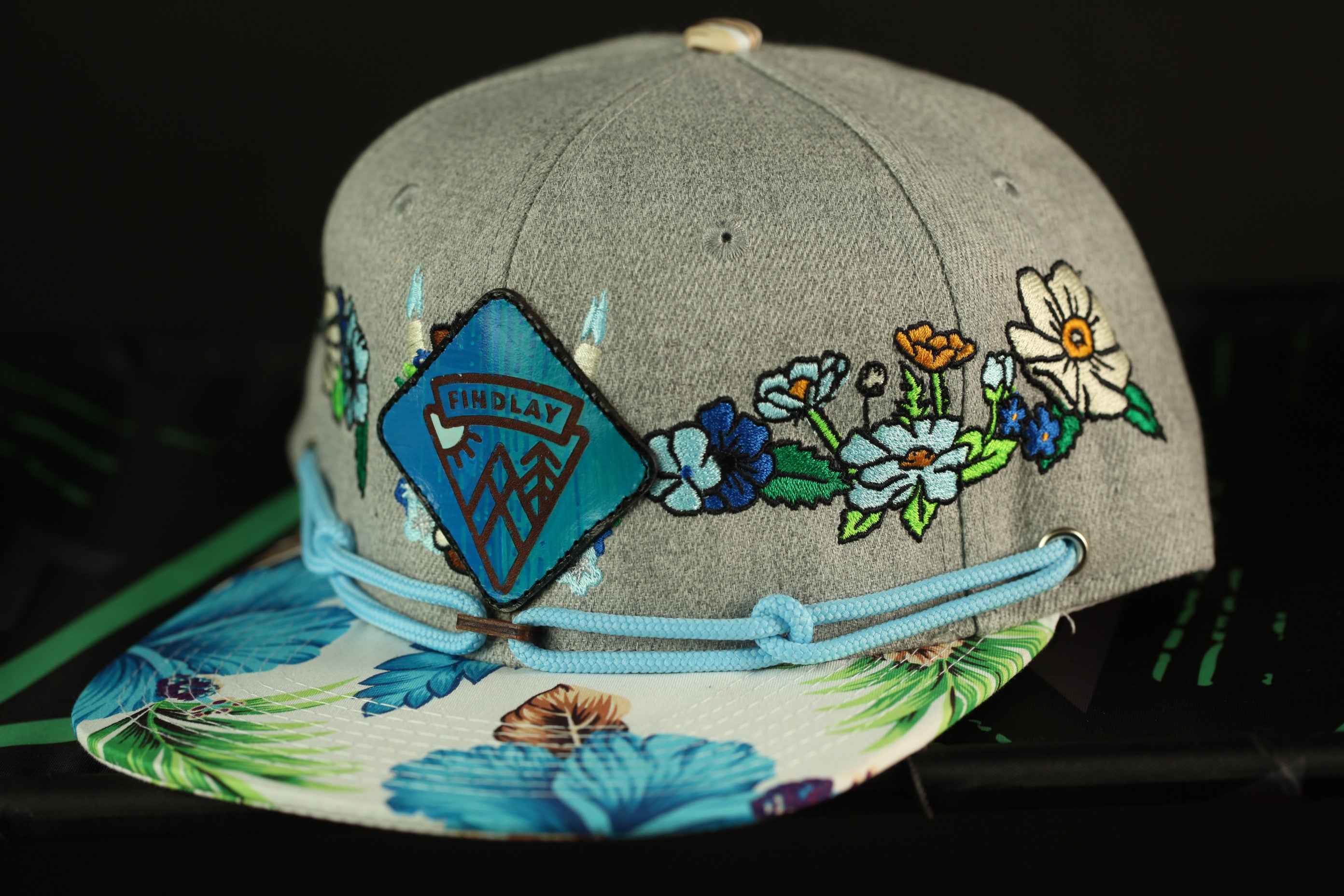 A gray baseball cap with a floral pattern and a small patch on the front.
