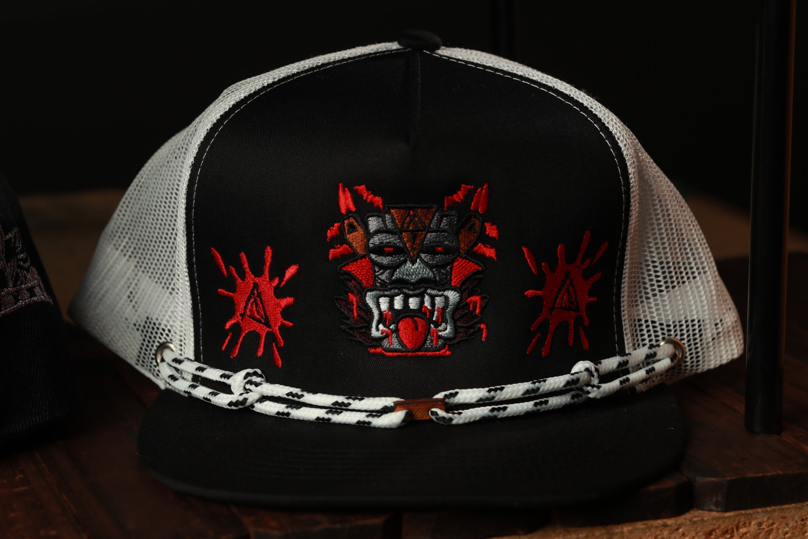 A black and white baseball cap with a red and black dragon design on the front.