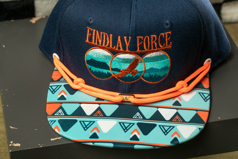 A navy blue baseball cap with a colorful geometric pattern and the text "Findlay Force" printed on it.