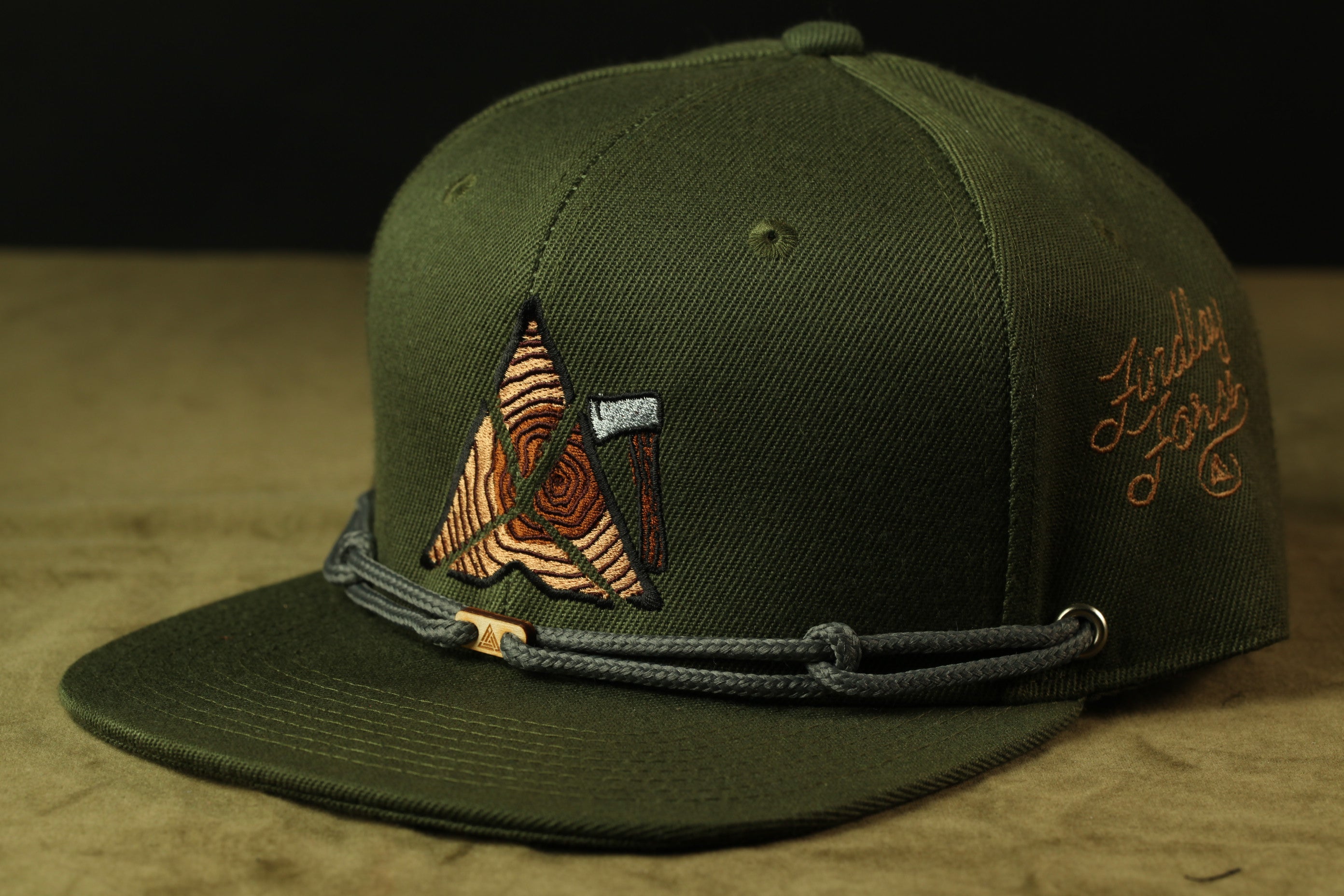 A green baseball cap with a unique embroidered design on the front.