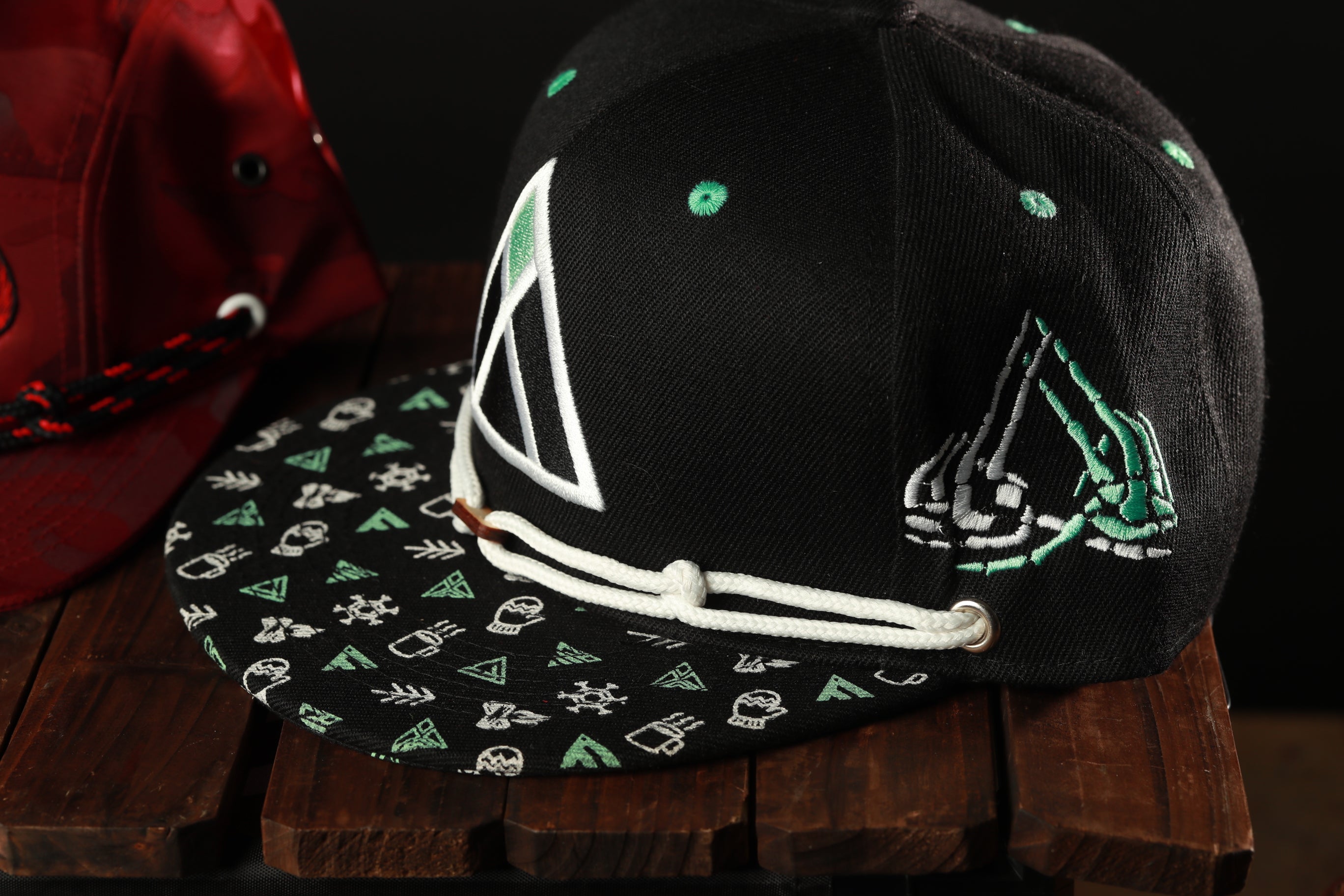 A black baseball cap with a patterned fabric and a white triangle design on the front, placed on a wooden surface.