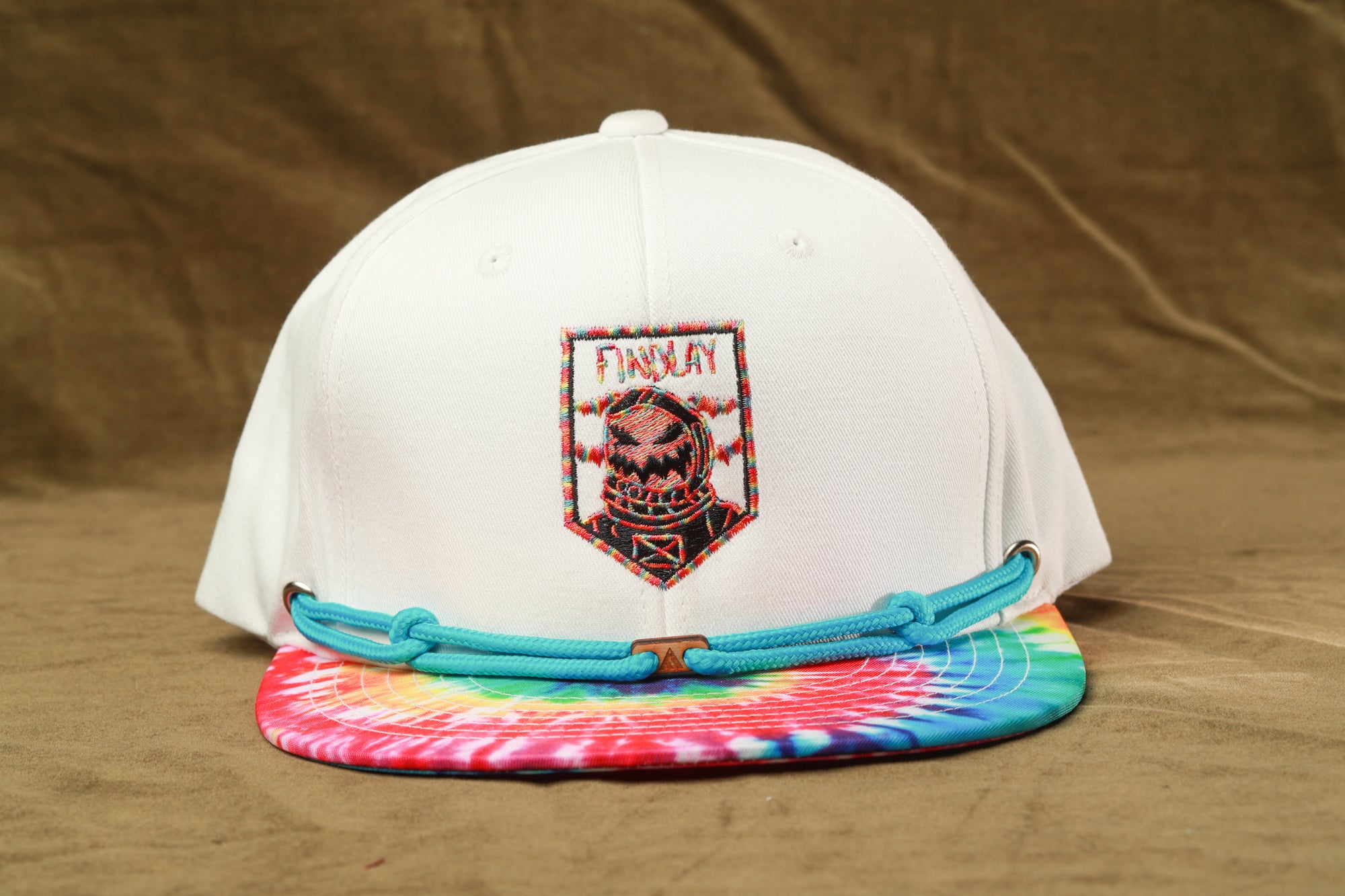 A white baseball cap with a colorful tie-dye pattern and a patch featuring a skull and crossbones design.