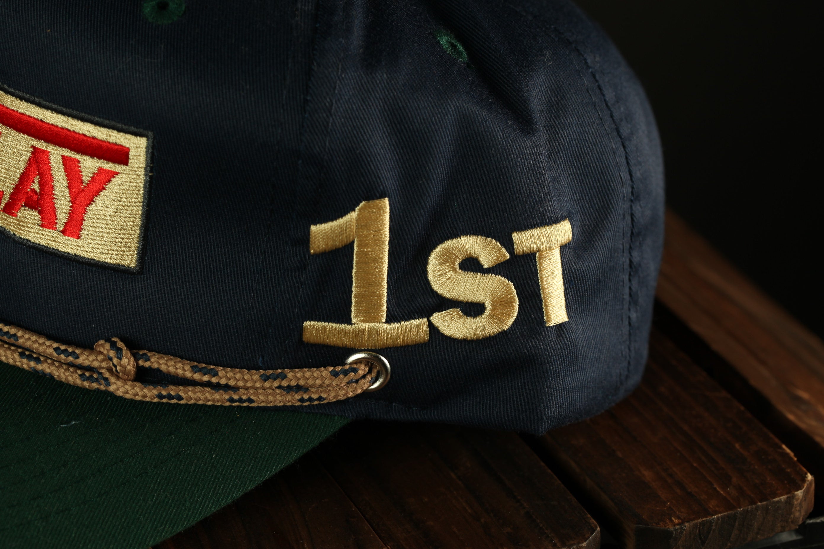 A close-up view of a dark blue baseball cap with the number "1st" embroidered on it.