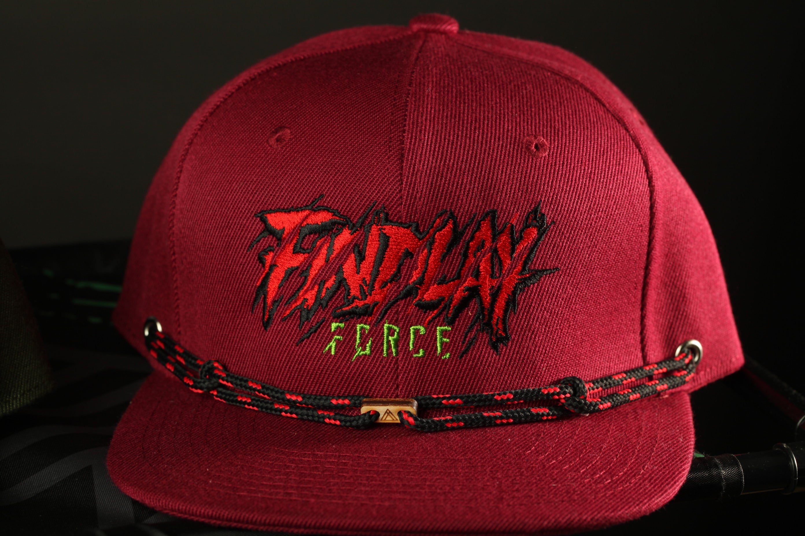 A maroon baseball cap with a black and red braided strap and the text "FINDY FORCE" printed on it.