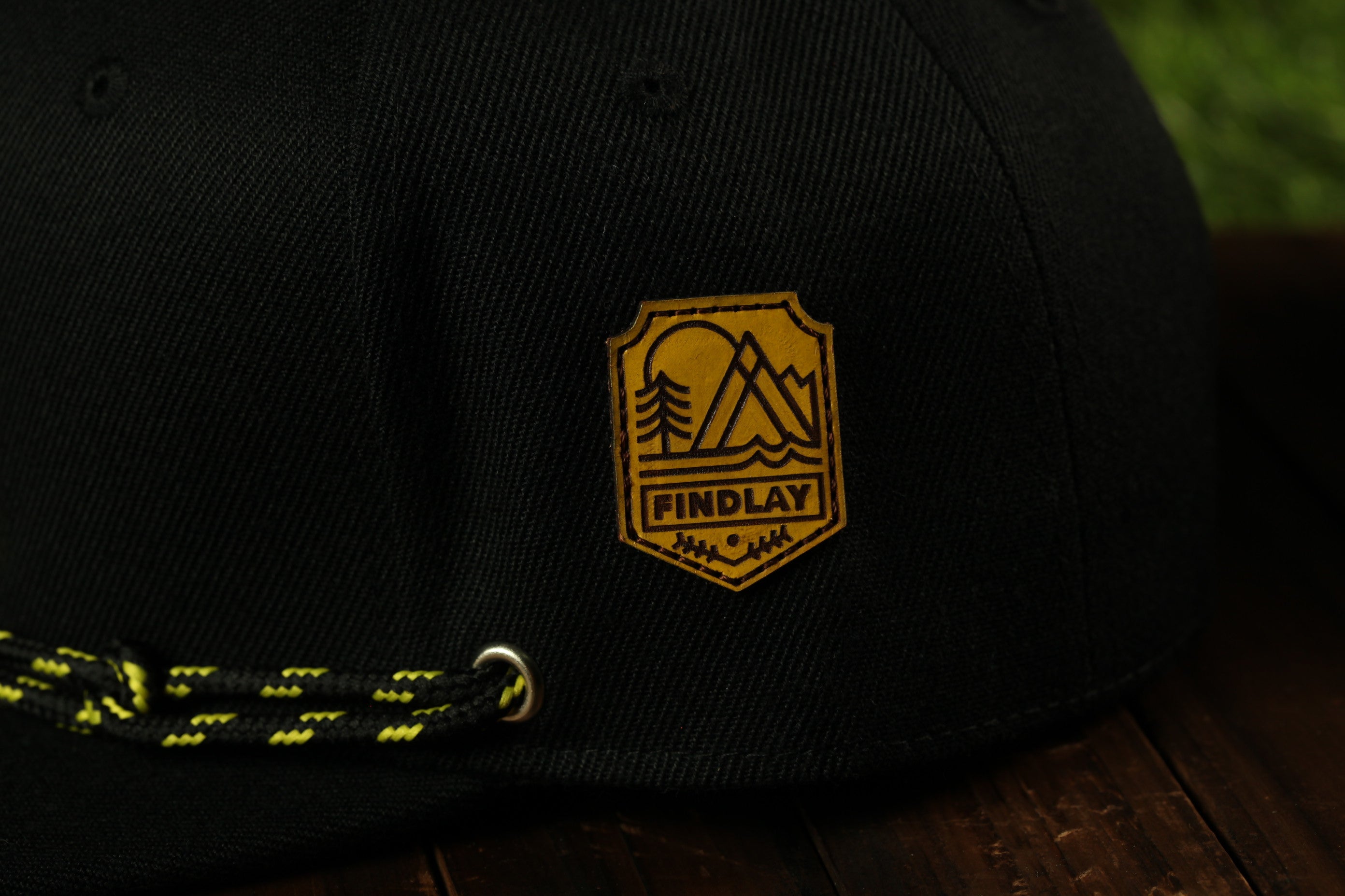A close-up view of a black baseball cap with a yellow and black logo on the front.