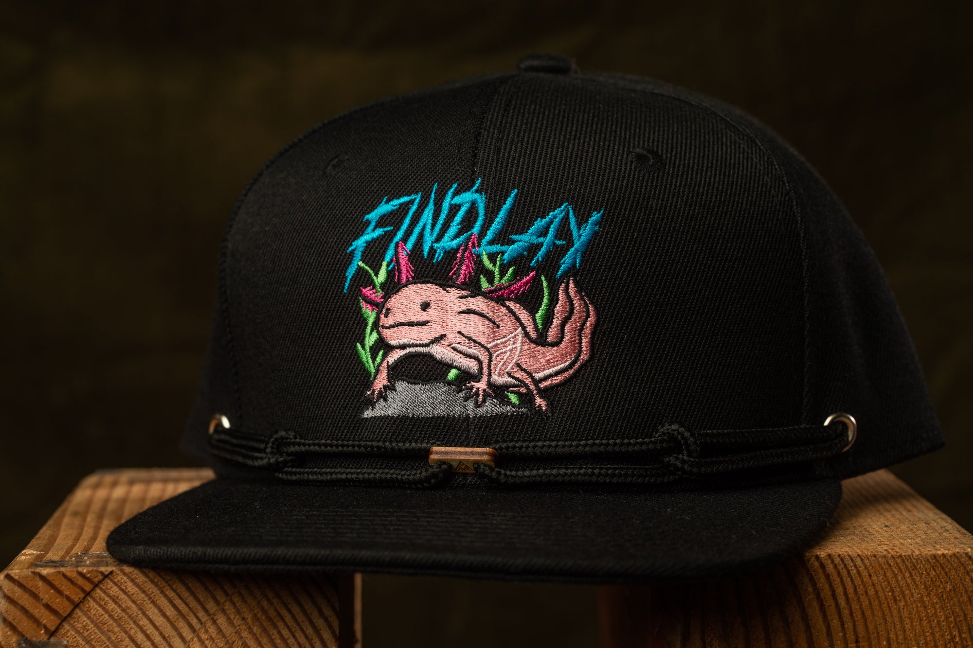 A black baseball cap with a graphic of a pink alligator on it, along with the text "FIND LAY" printed on it.