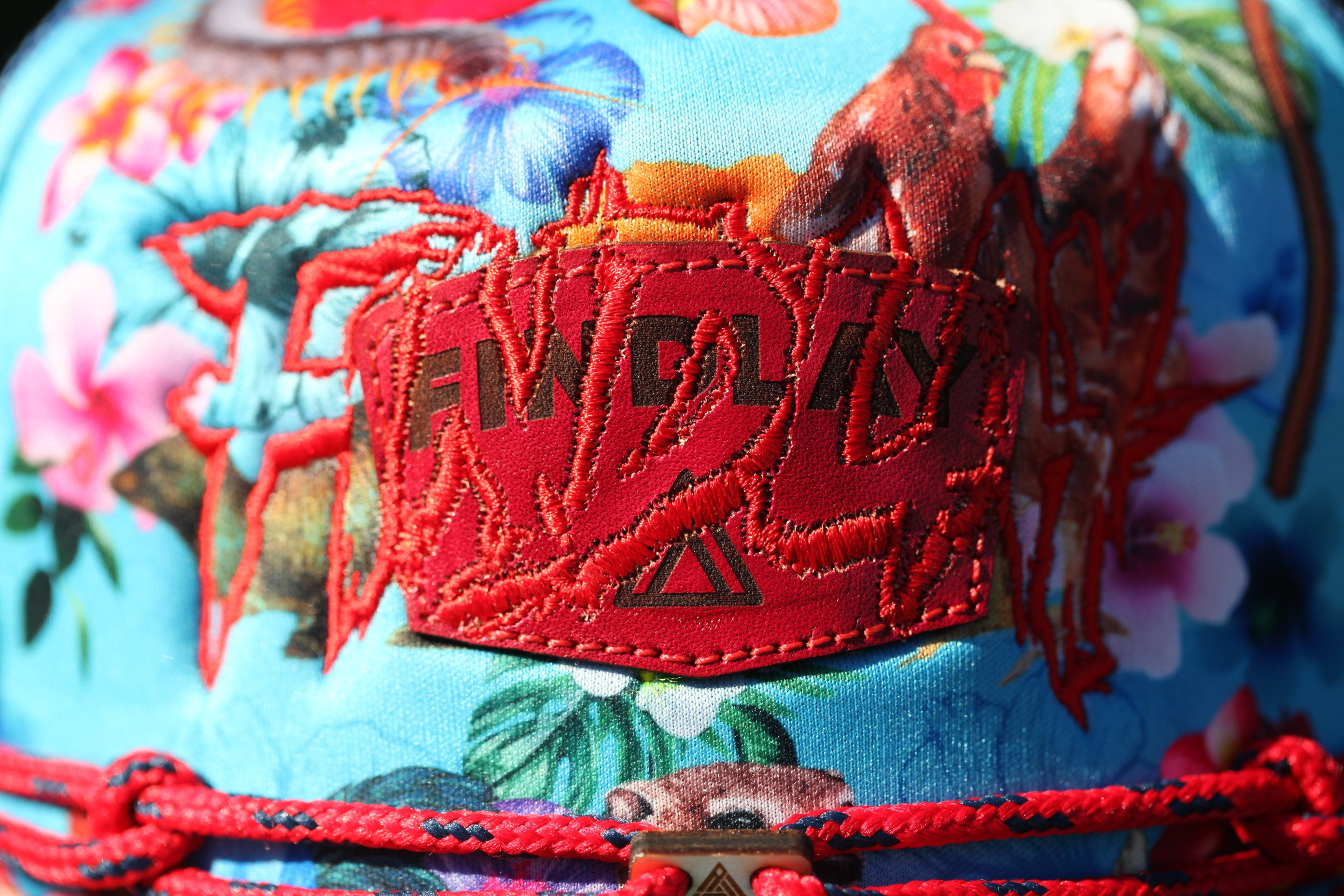 a close-up view of a vibrant, colorful fabric with a red embroidered logo prominently displayed on it.
