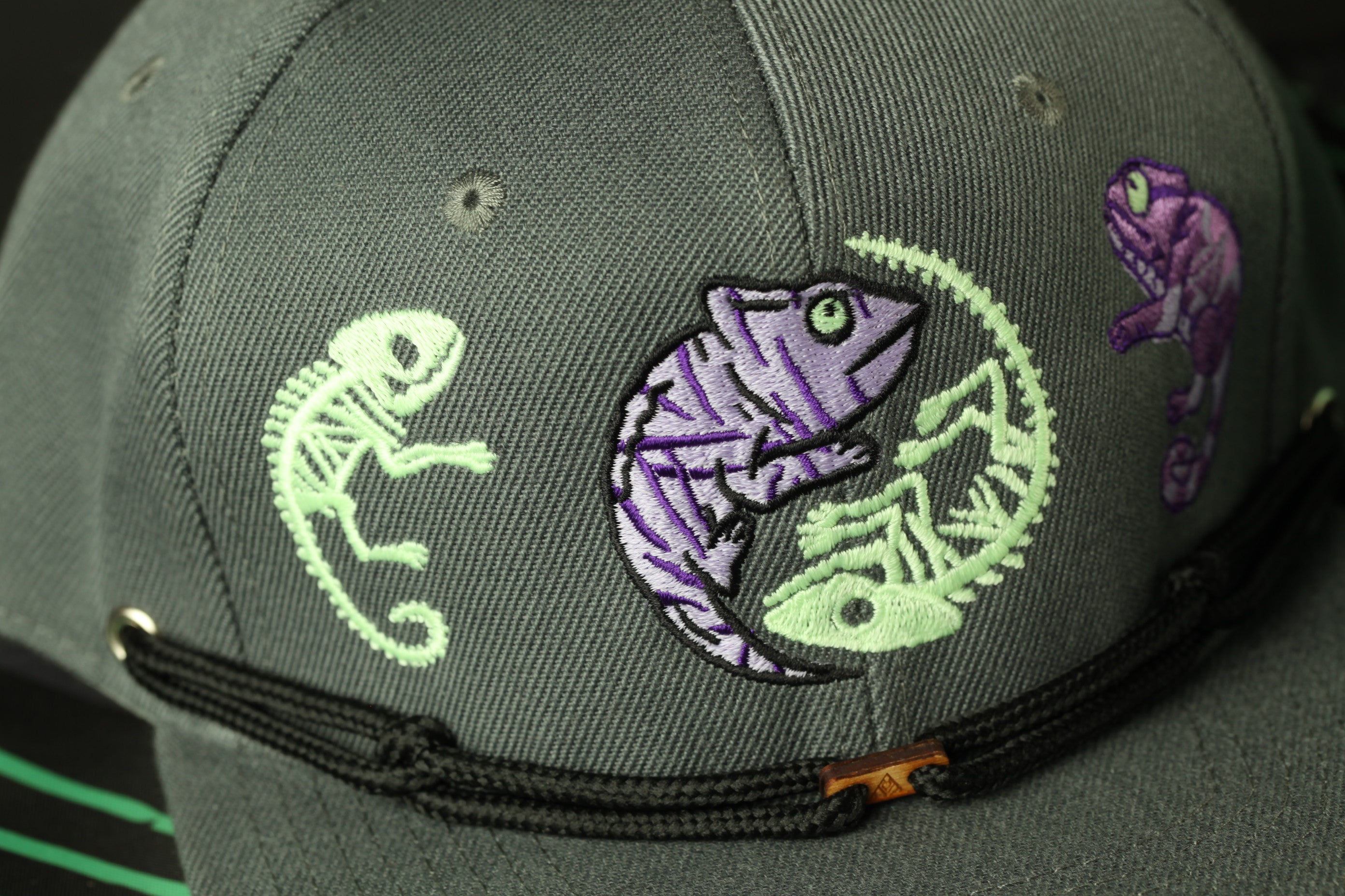 a gray baseball cap with a unique design of three chameleons in different colors - purple, green, and white.
