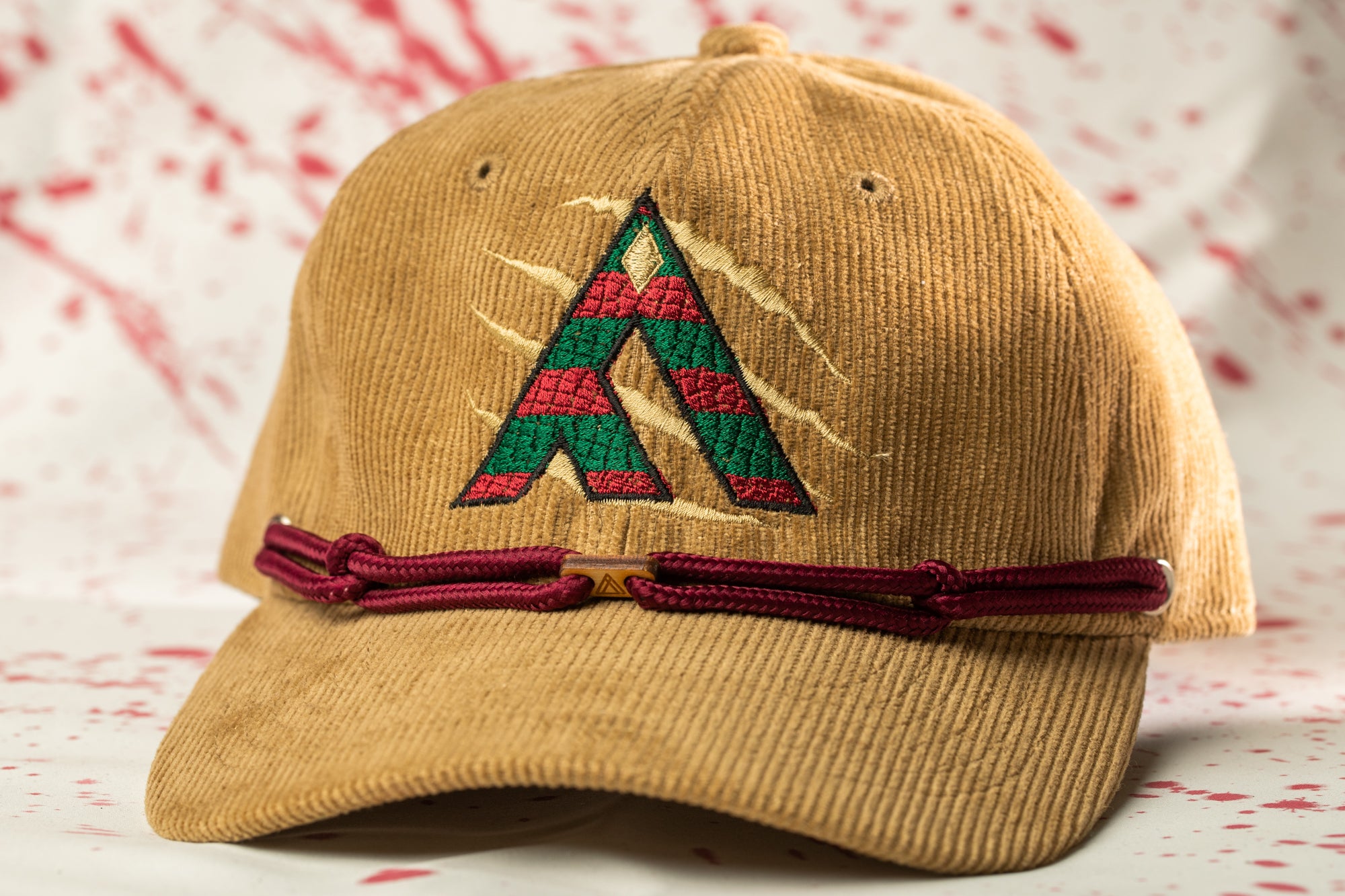 A brown baseball cap with a red and green embroidered logo on the front.