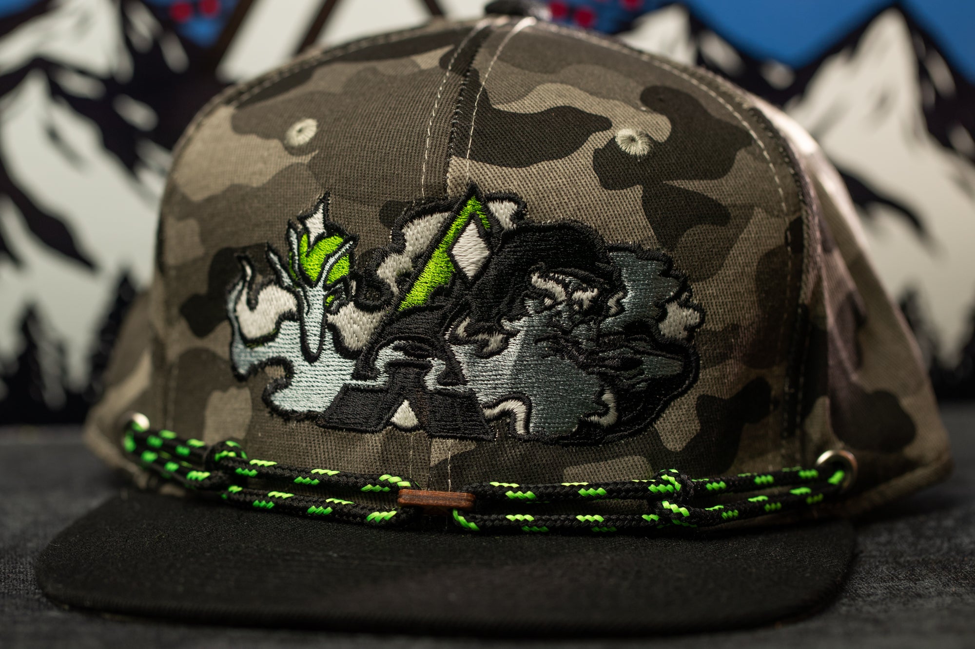 A camouflage baseball cap with a graphic design on the front.